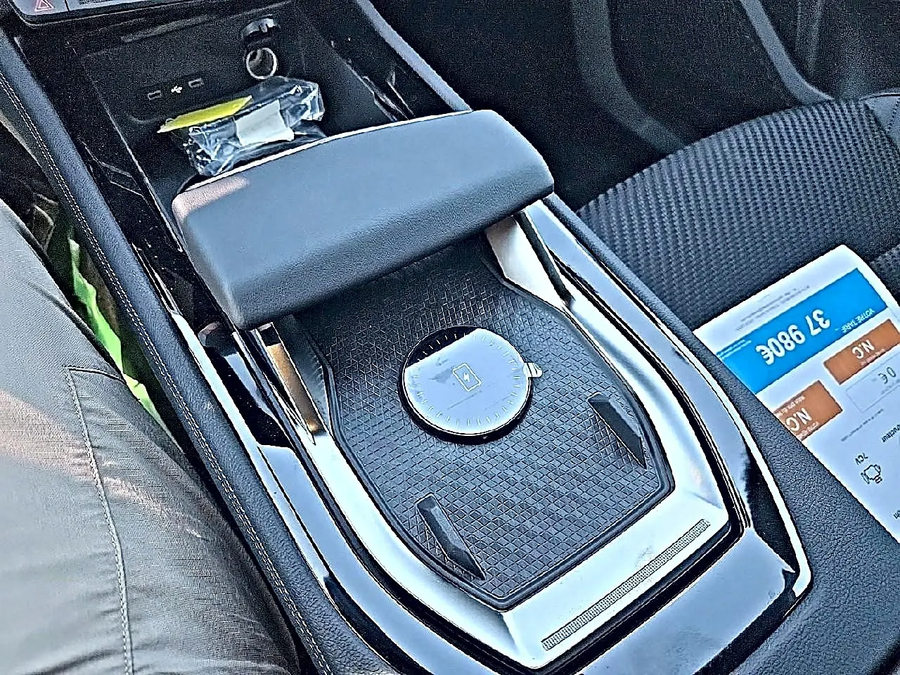 Gros plan sur l'accoudoir central noir et la console centrale du Renault Austral blanc nacré, intérieur tissu carbone alcantara.