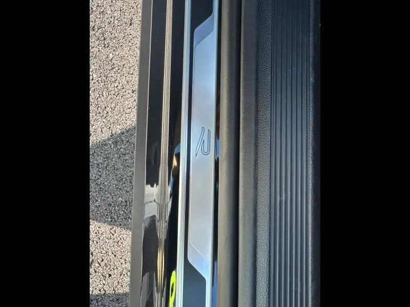 Gros plan sur la plaque de seuil de porte noire nacrée du Volkswagen T-Roc 1.5 TSI Evo2 R-Line avec logo R lumineux.
