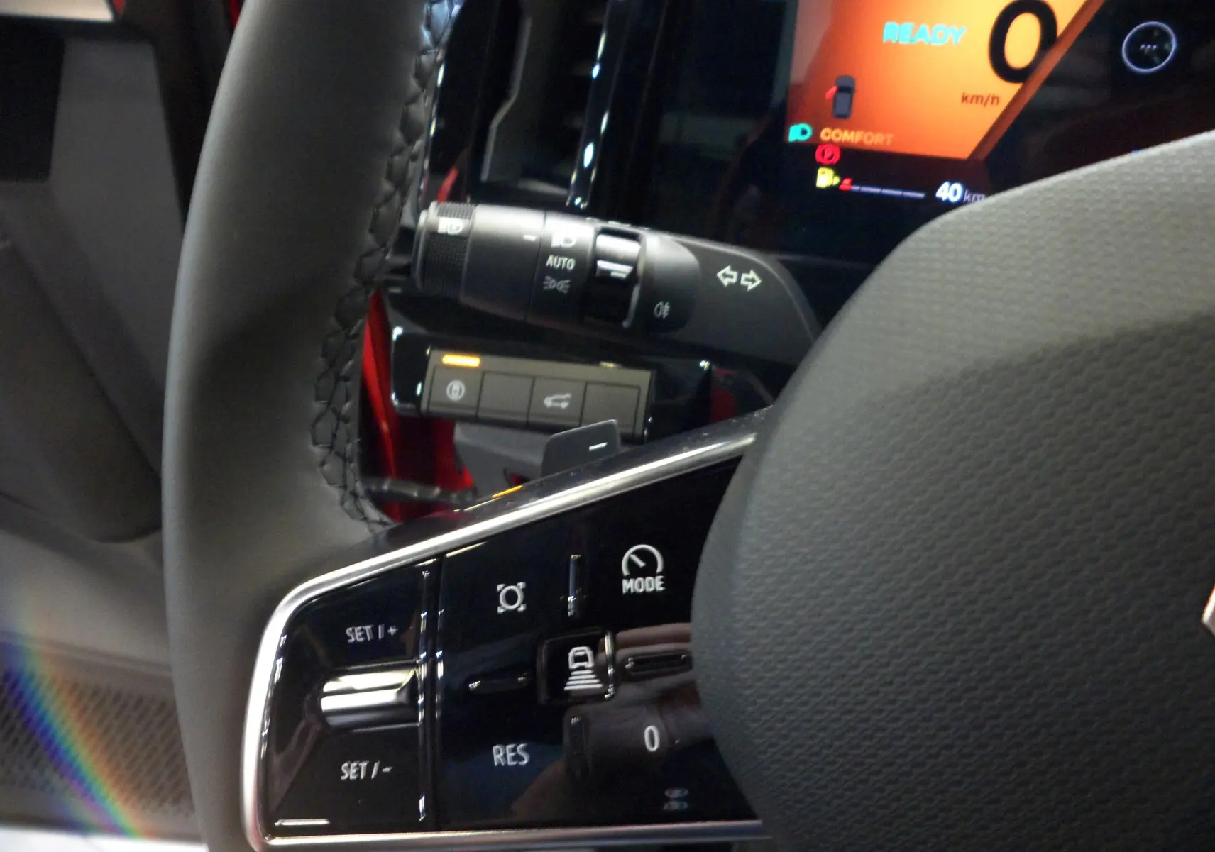 Gros plan sur le volant du Renault Rafale E-Tech rouge flamme, montrant les commandes intégrées et l'affichage numérique en arrière-plan.