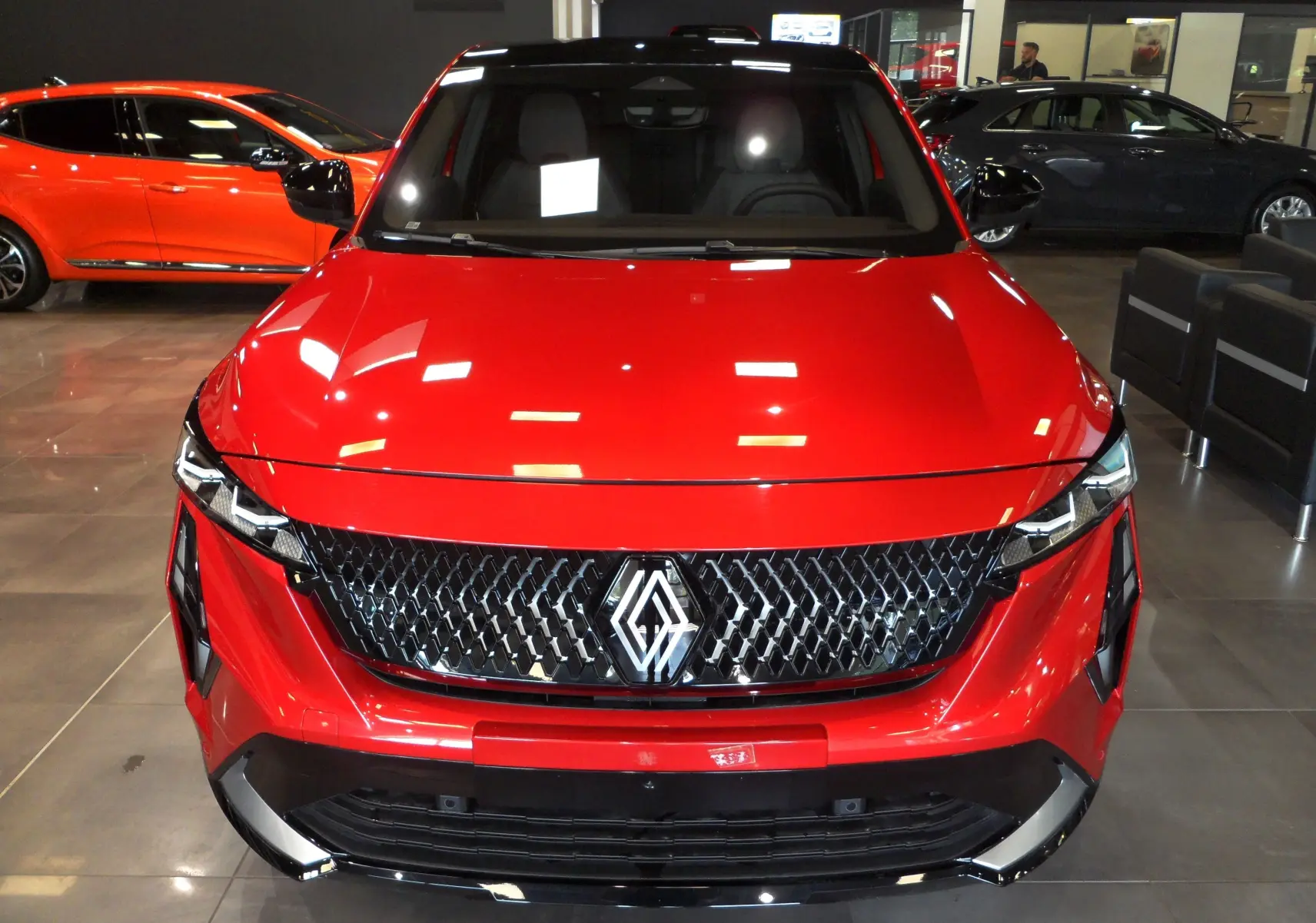 Vue frontale du Renault Rafale E-Tech Full Hybrid 200 ch en Rouge Flamme avec toit noir, mettant en valeur sa calandre distinctive.