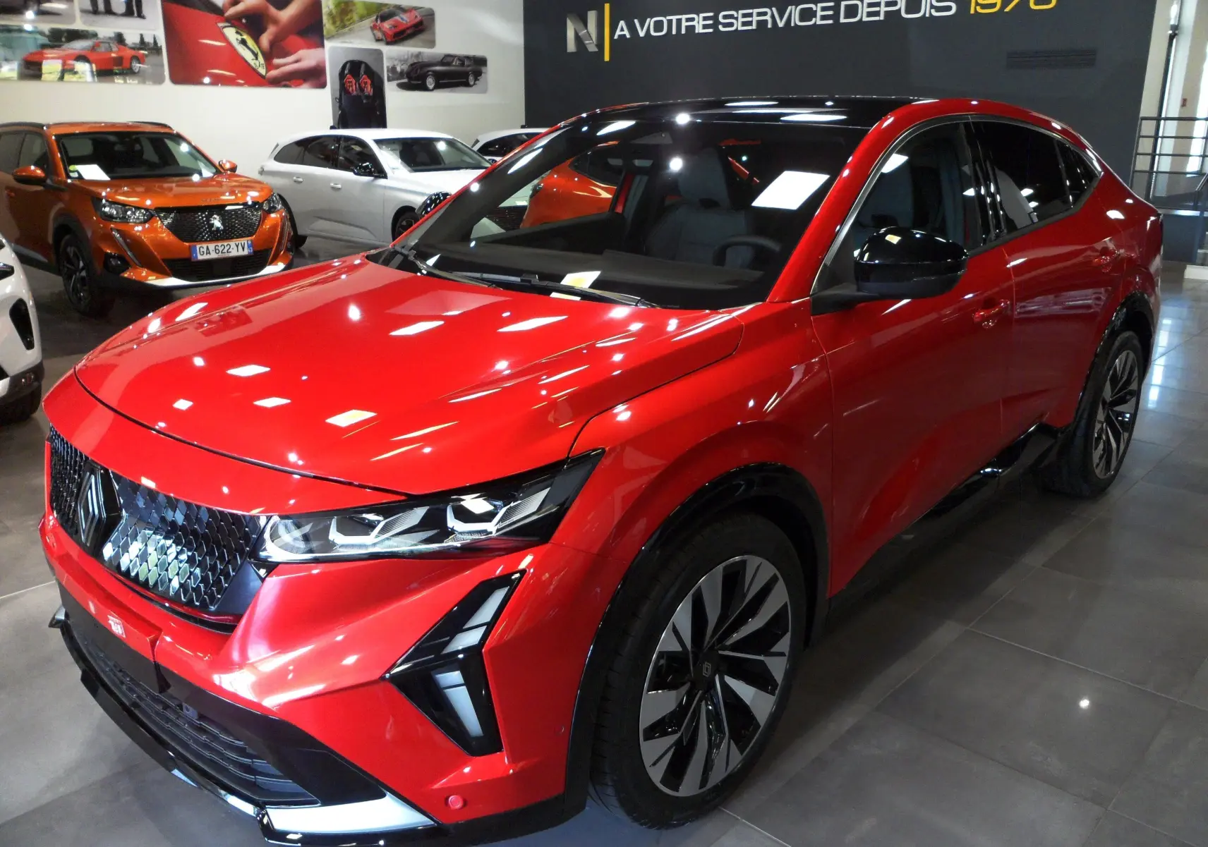 Renault Rafale E-Tech hybride rouge flamme avec toit noir, vue 3/4 avant droit en showroom lumineux.