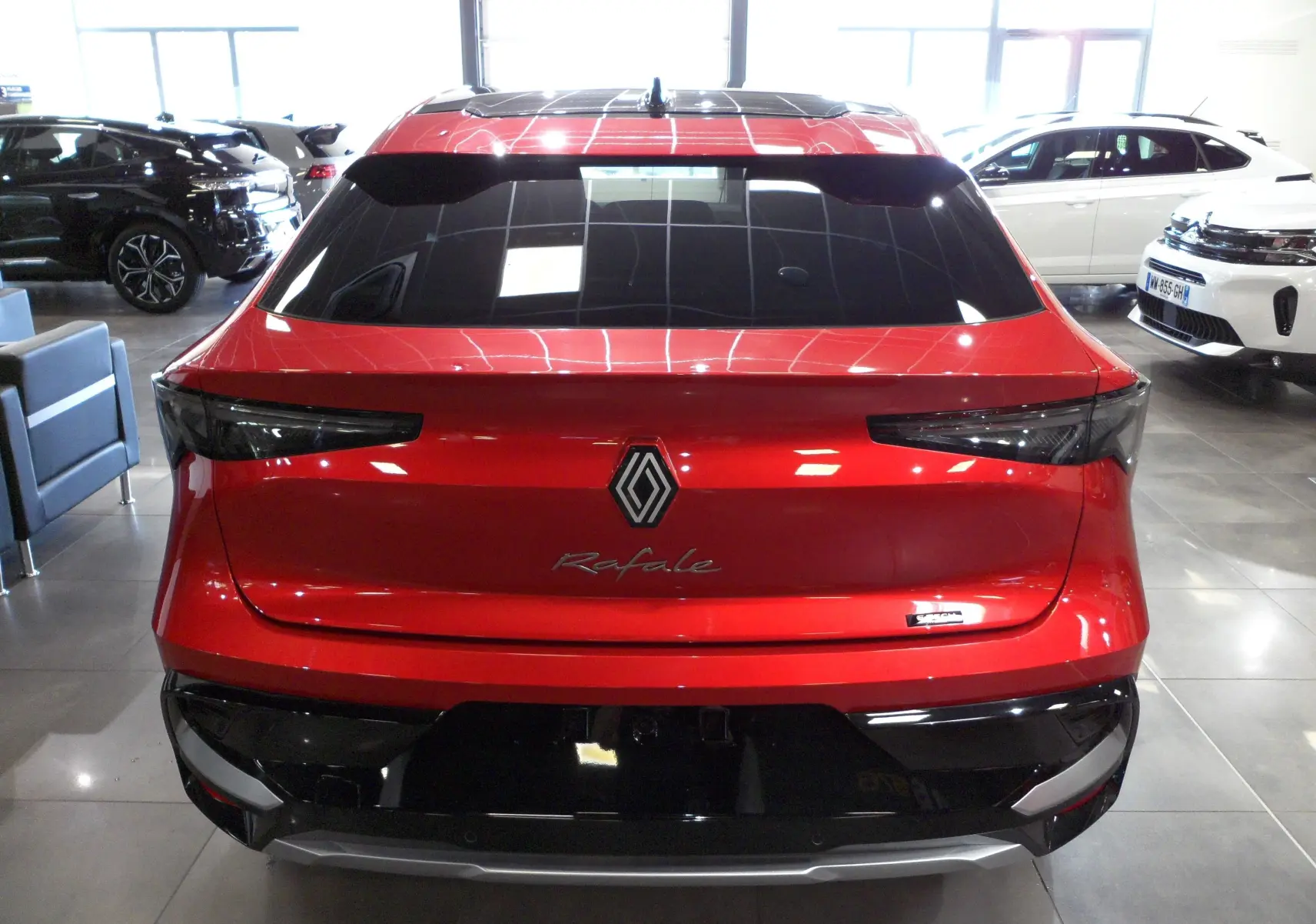 Vue arrière du Renault Rafale rouge Flamme avec toit noir et feux arrière étirés en intérieur de showroom.
