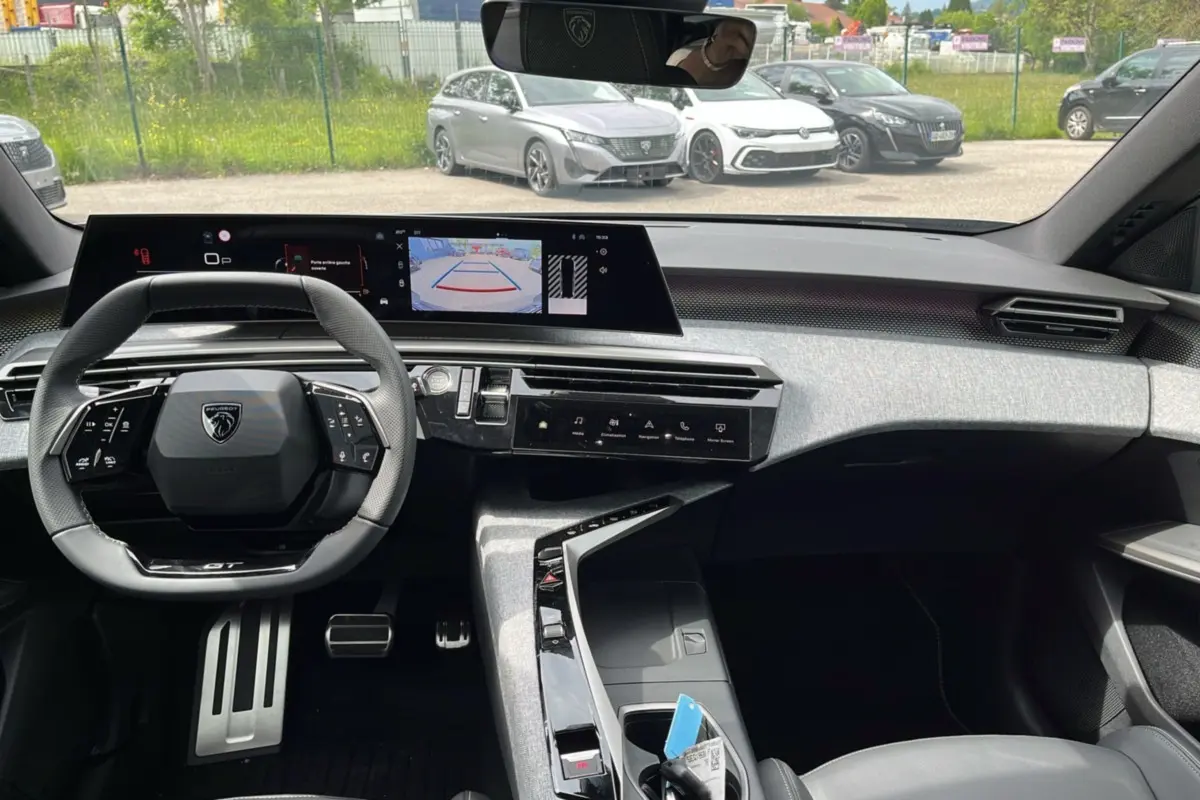 Intérieur du Peugeot 3008 Hybrid 2025 vu de face, tableau de bord moderne avec écran large et volant compact noir.