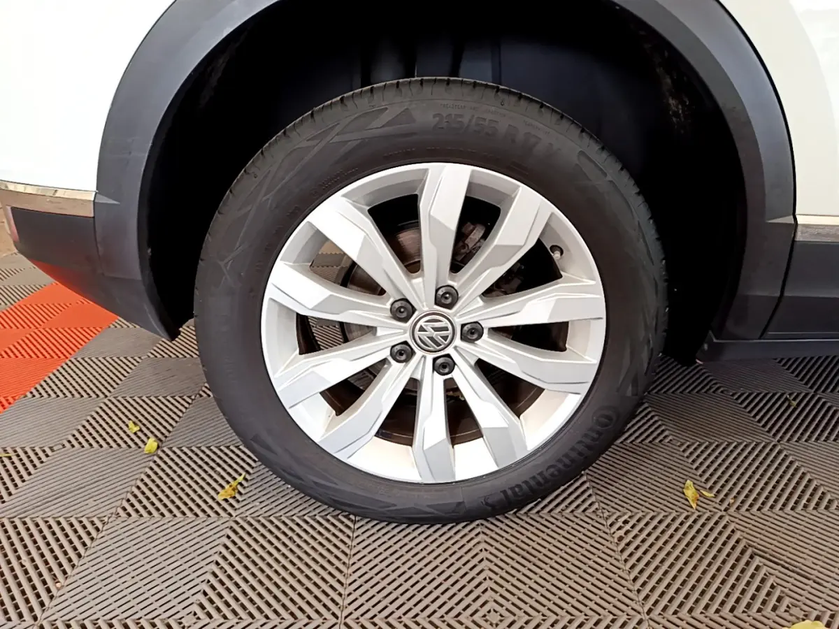 Gros plan sur la roue avant droite blanche du Volkswagen T-Roc 1.5 TSI 150 EVO CARAT DSG7 avec jante alliage argentée.