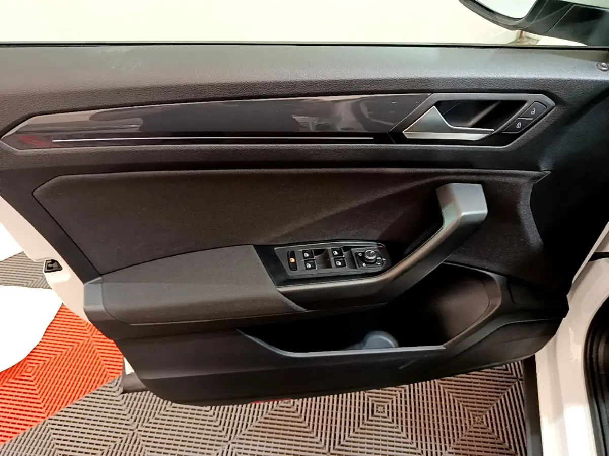 Vue intérieure du panneau de porte côté conducteur du Volkswagen T-Roc blanc, avec commandes de vitres et verrouillage.