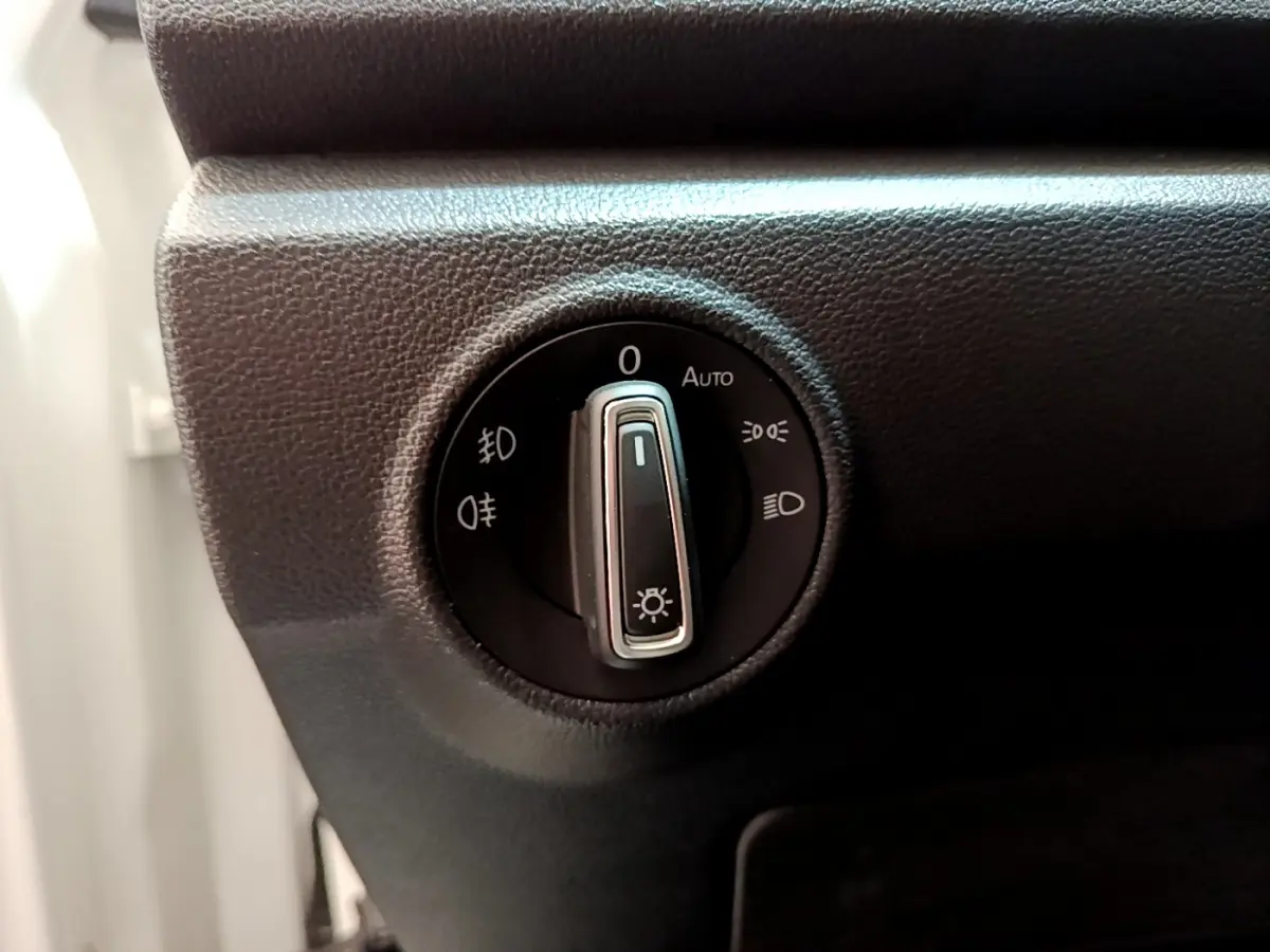 Gros plan sur le sélecteur d'éclairage noir du tableau de bord du Volkswagen T-Roc blanc, côté gauche.