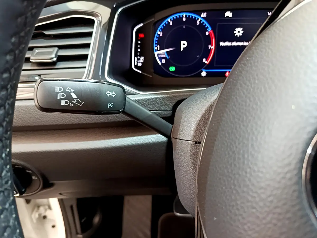 Gros plan sur le volant noir et le combiné d'instruments digital du Volkswagen T-Roc 1.5 TSI blanc, affichage multifonctions visible.