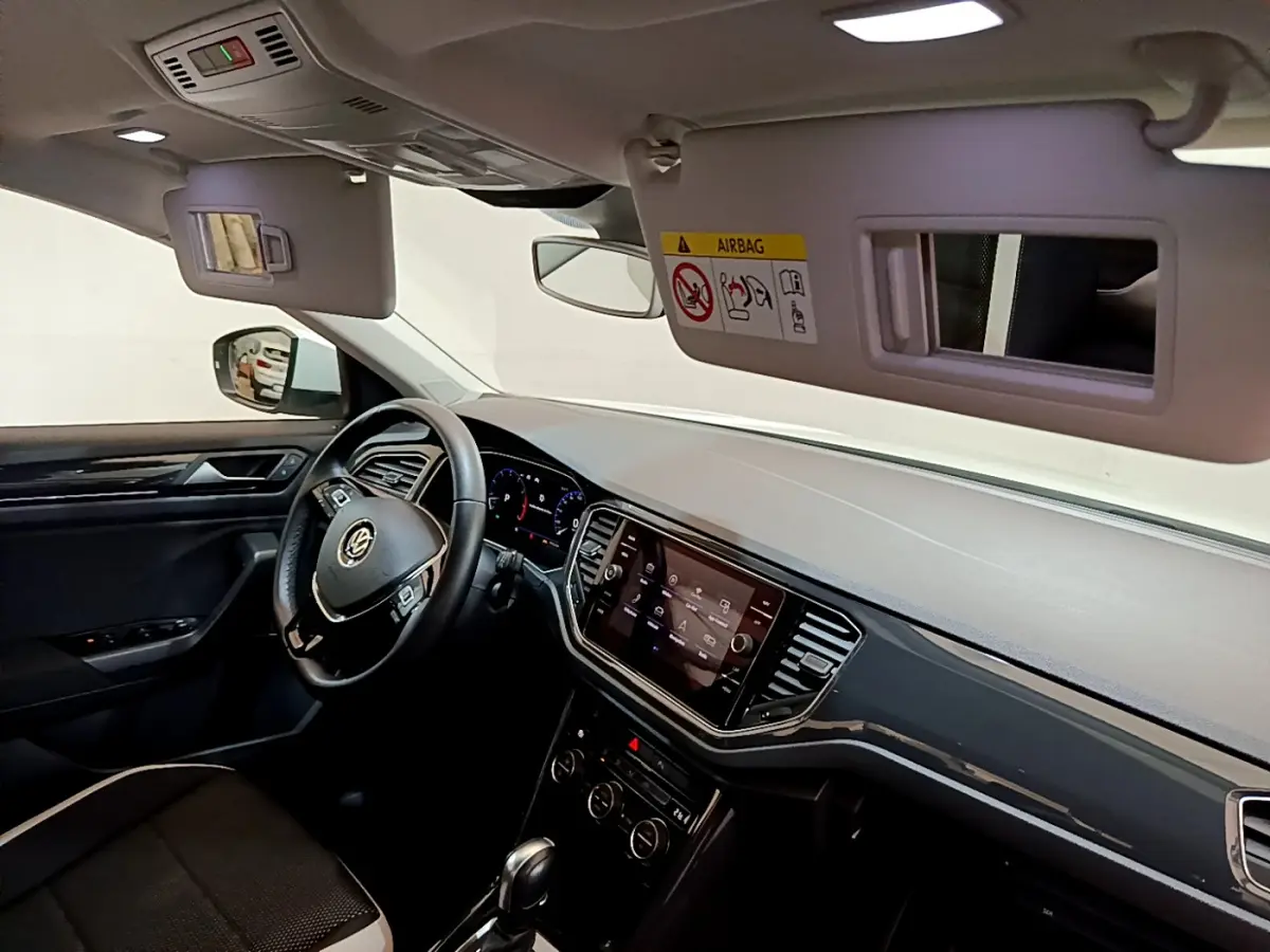 Intérieur du Volkswagen T-Roc 1.5 TSI 2020 vu côté conducteur, tableau de bord noir avec écran tactile et volant cuir.