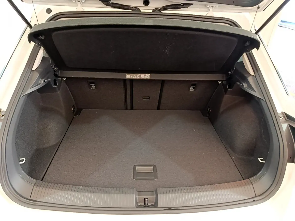 Coffre ouvert du Volkswagen T-Roc blanc, vue arrière montrant l’espace de chargement vide et la tablette de séparation.