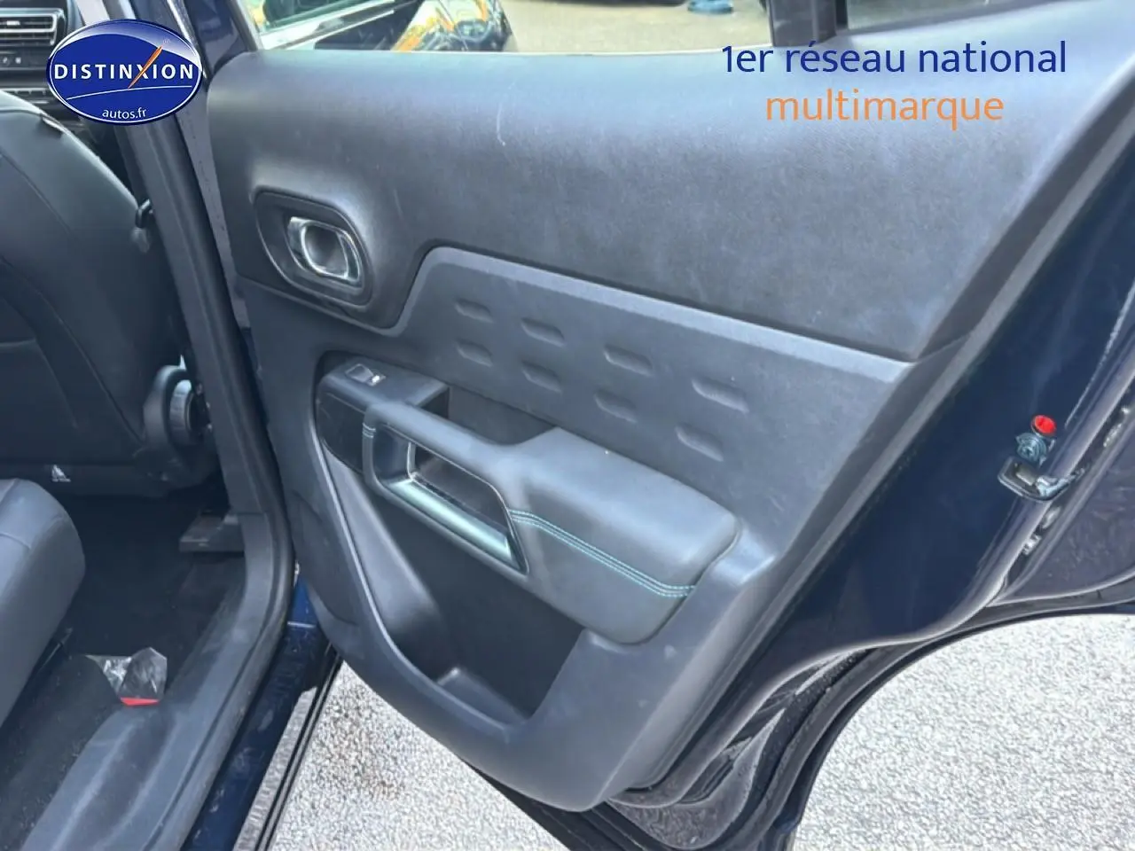 Vue intérieure du côté arrière gauche de la porte d’un Citroën C5 Aircross bleu eclipse avec accoudoir et commande de vitre.