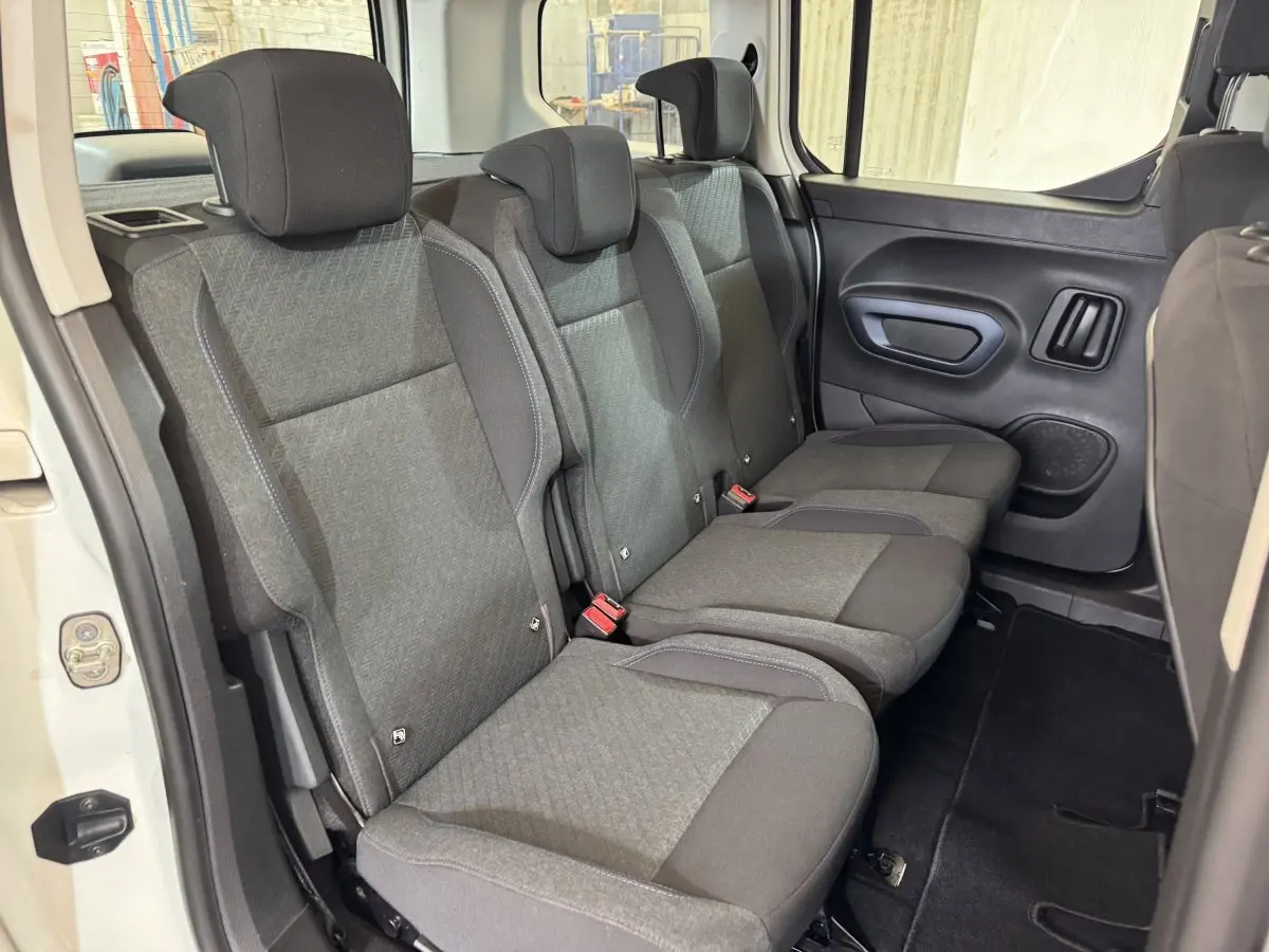 Vue intérieure des sièges arrière gris du Peugeot Rifter BlueHDi 100 Allure blanc, avec porte latérale ouverte.