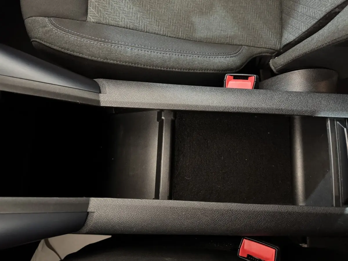 Vue rapprochée de la console centrale noire entre les sièges avant gris du Peugeot Rifter blanc 2019.