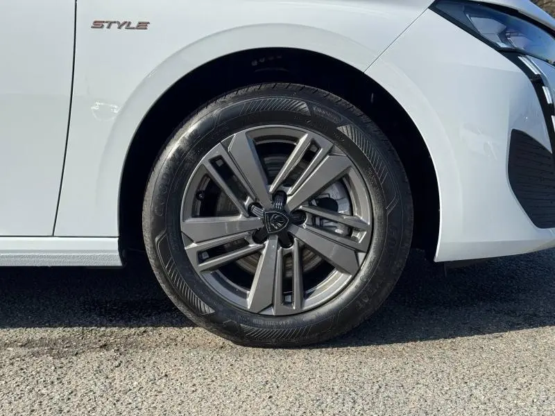 Gros plan sur la roue avant gauche et l'aile blanche Okénite d'une Peugeot 308 Style avec jante alu et logo Peugeot.