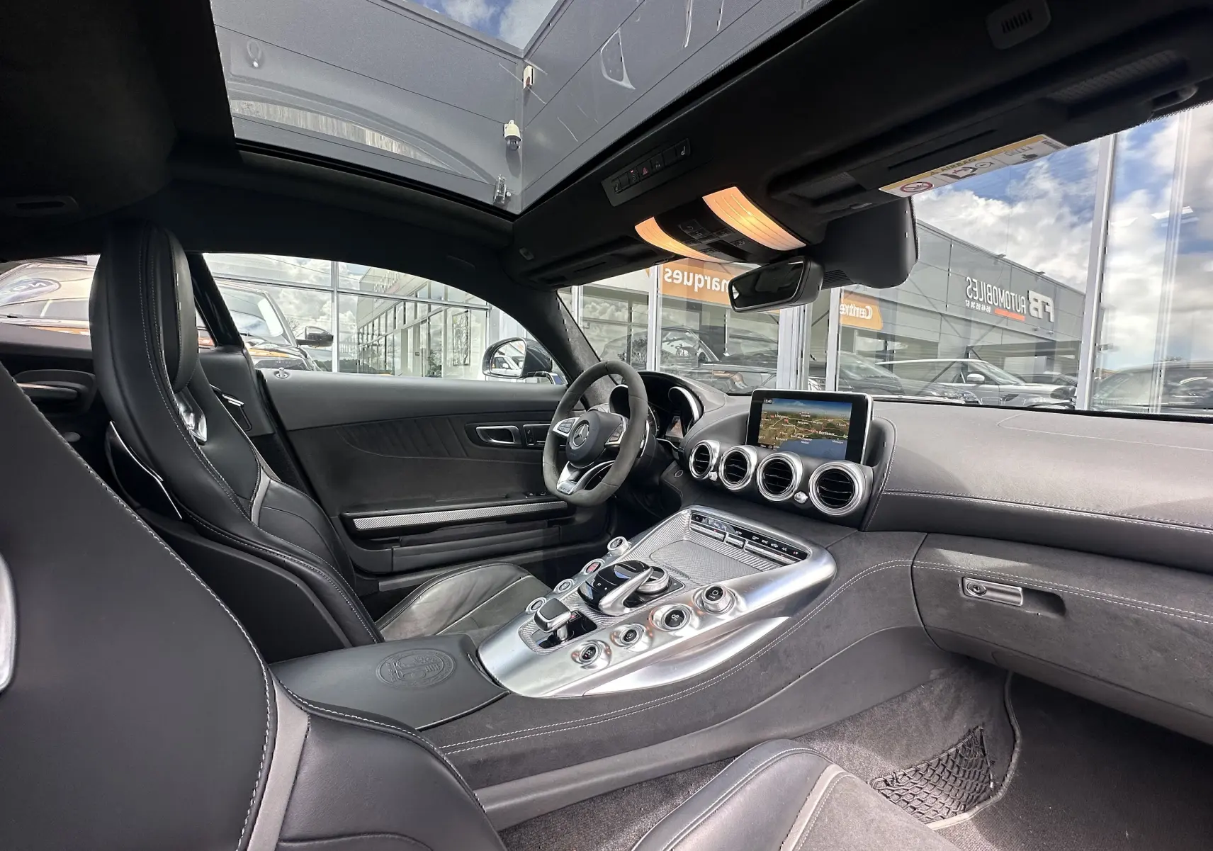 Intérieur noir du Mercedes AMG GT 2015 vu côté conducteur, avec console centrale alu et toit panoramique.