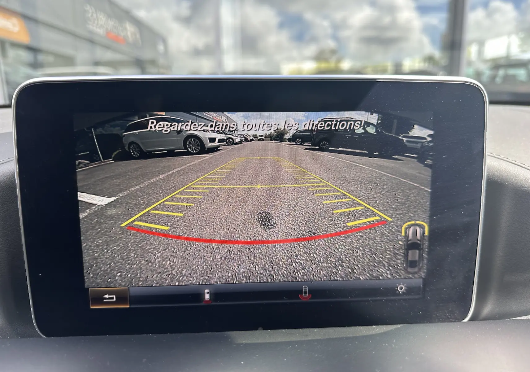 Vue de la caméra de recul du Mercedes AMG GT gris foncé, affichant le marquage au sol et les véhicules en arrière-plan.