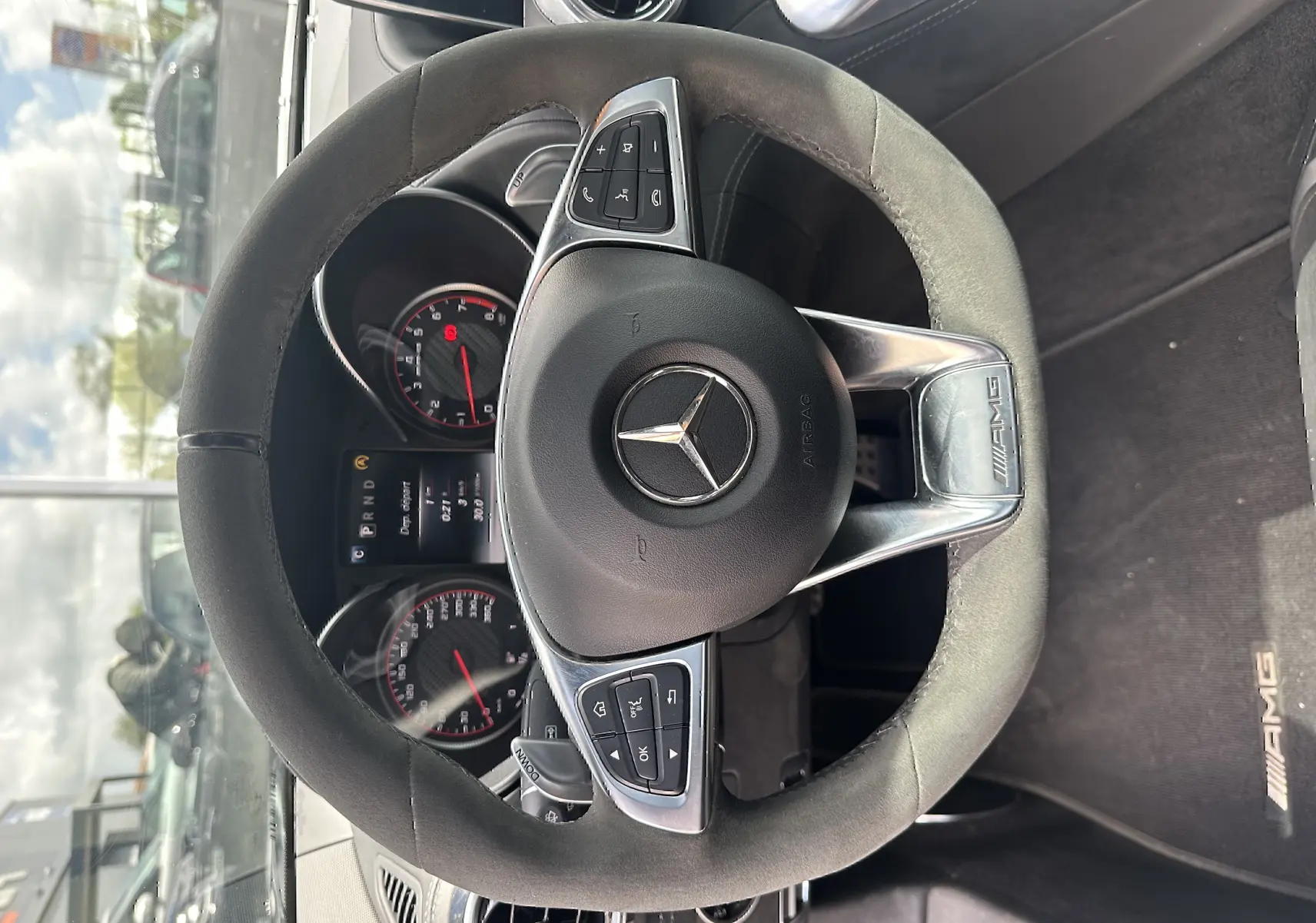 Vue plongeante sur le volant AMG en alcantara noir et le tableau de bord du Mercedes AMG GT gris foncé de 2015.