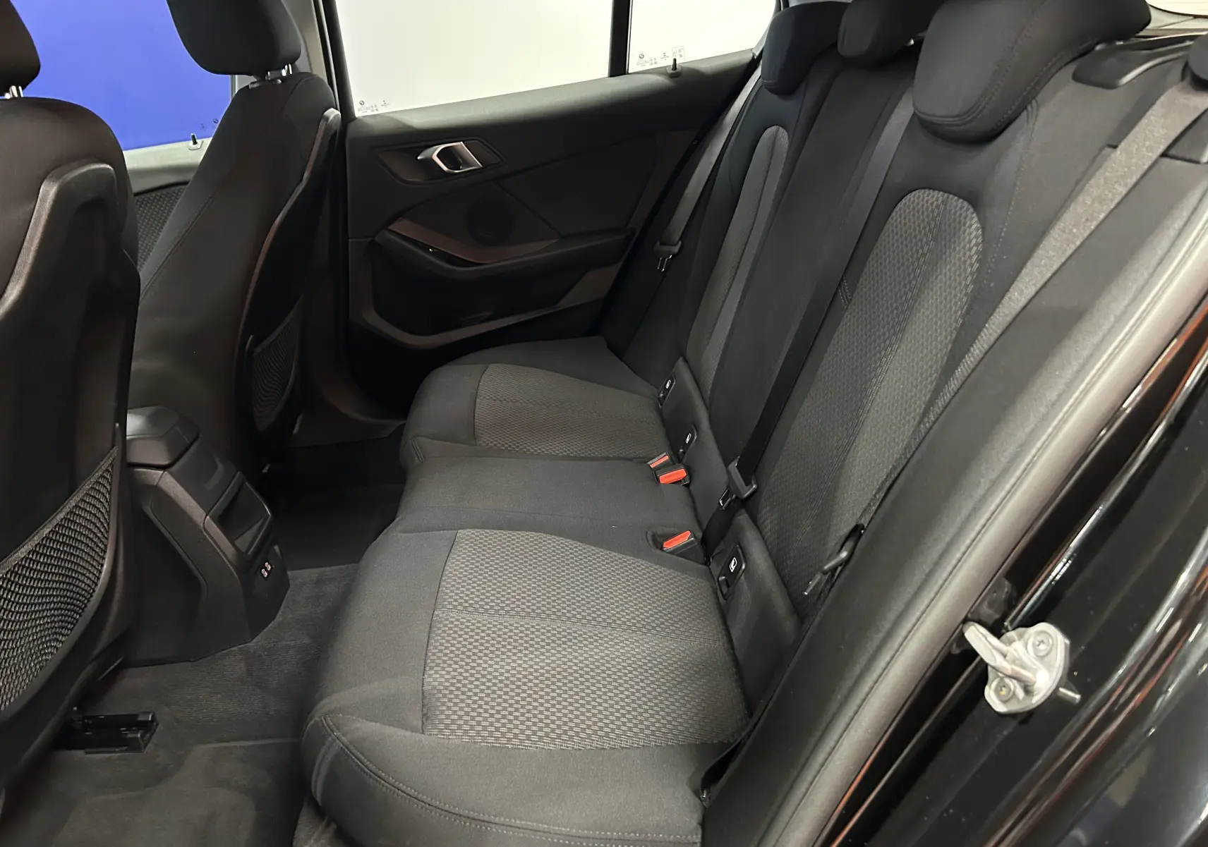 Vue intérieure côté droit des sièges arrière en tissu gris foncé d'une BMW Série 1 noire de 2023.