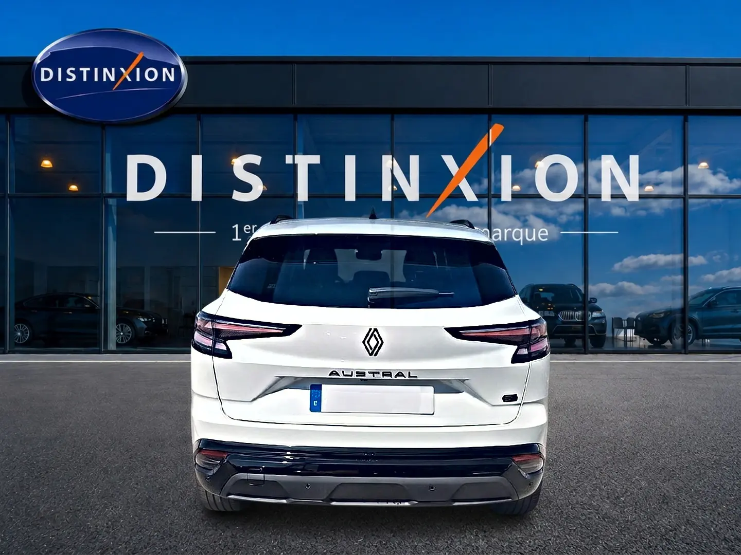 Vue arrière d'un Renault Austral blanc nacré 2026 avec feux LED et becquet arrière, devant une vitrine Distinxion.