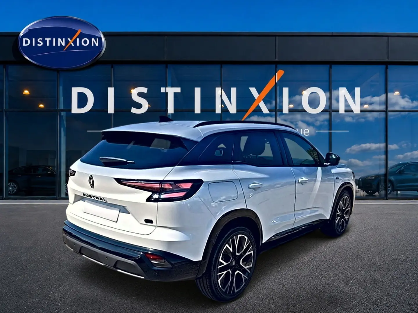 Vue 3/4 arrière droite du Renault Austral blanc nacré avec jantes alliage et toit noir devant une vitrine Distinxion.