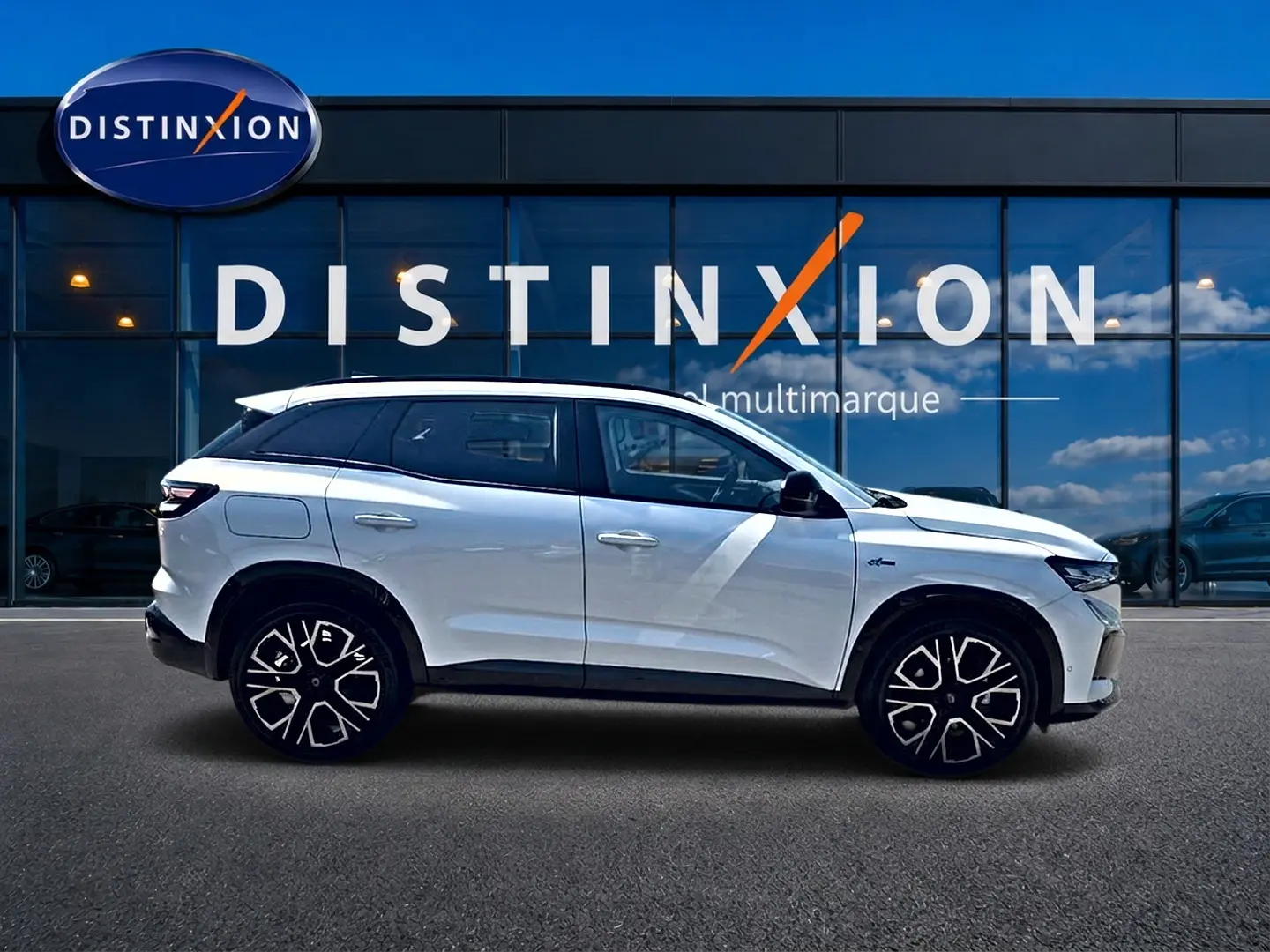 Renault Austral blanc nacré en profil droit, avec jantes alu et toit surélevé devant une vitrine Distinxion.