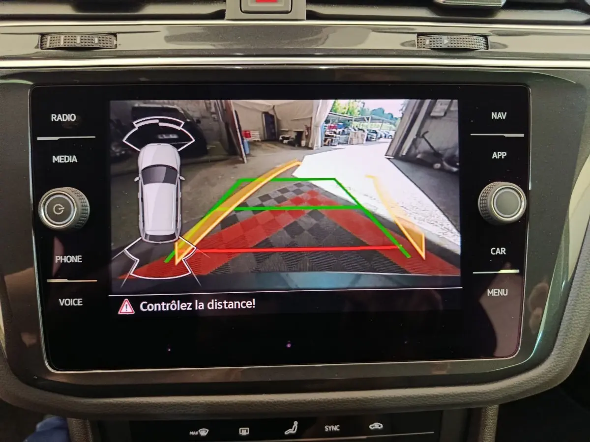 Écran tactile du Volkswagen Tiguan bleu montrant la caméra de recul avec guidage de trajectoire et alertes de distance.