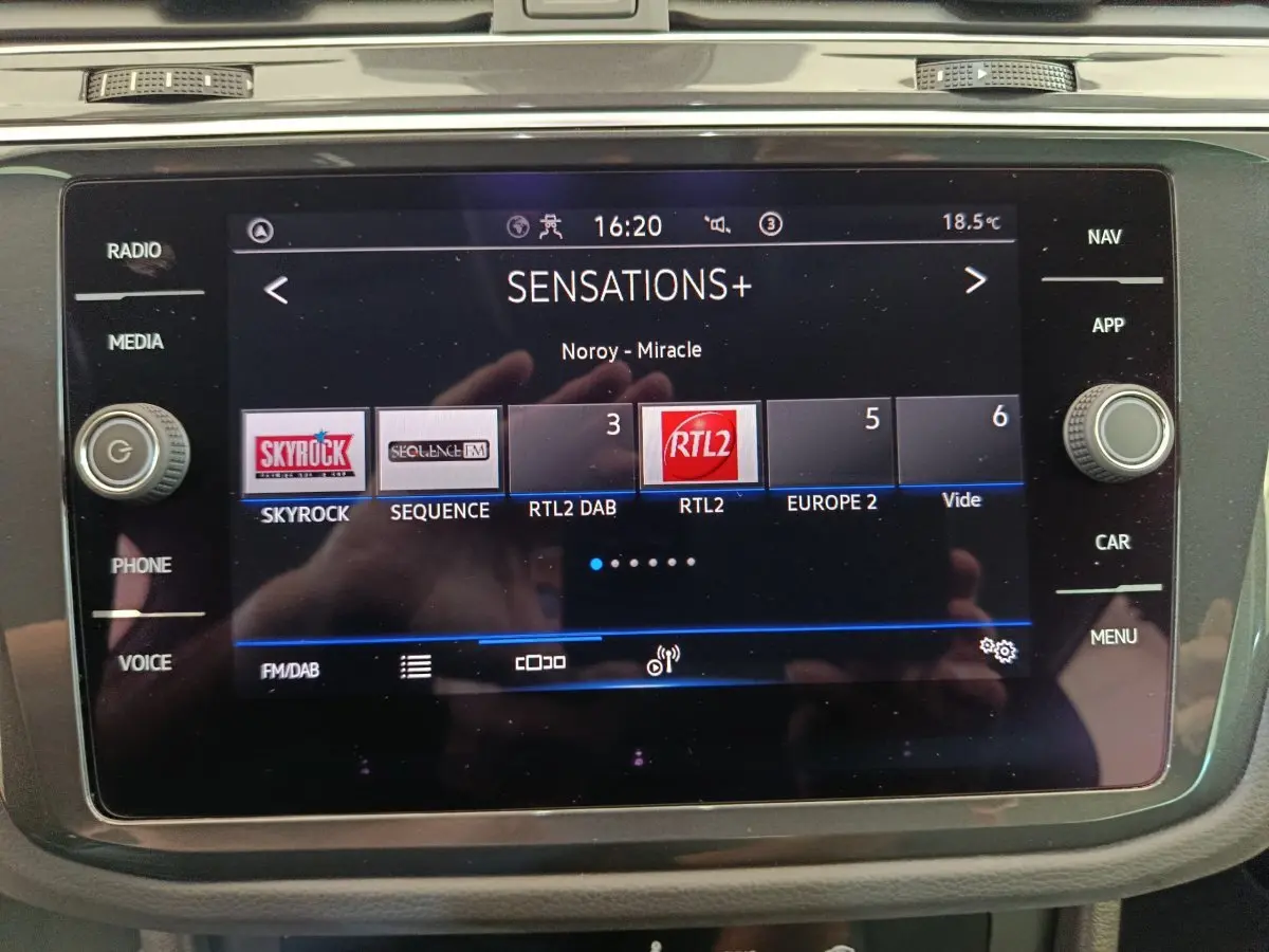 Écran tactile central du Volkswagen Tiguan bleu 2022 affichant les stations radio FM/DAB avec commandes latérales.