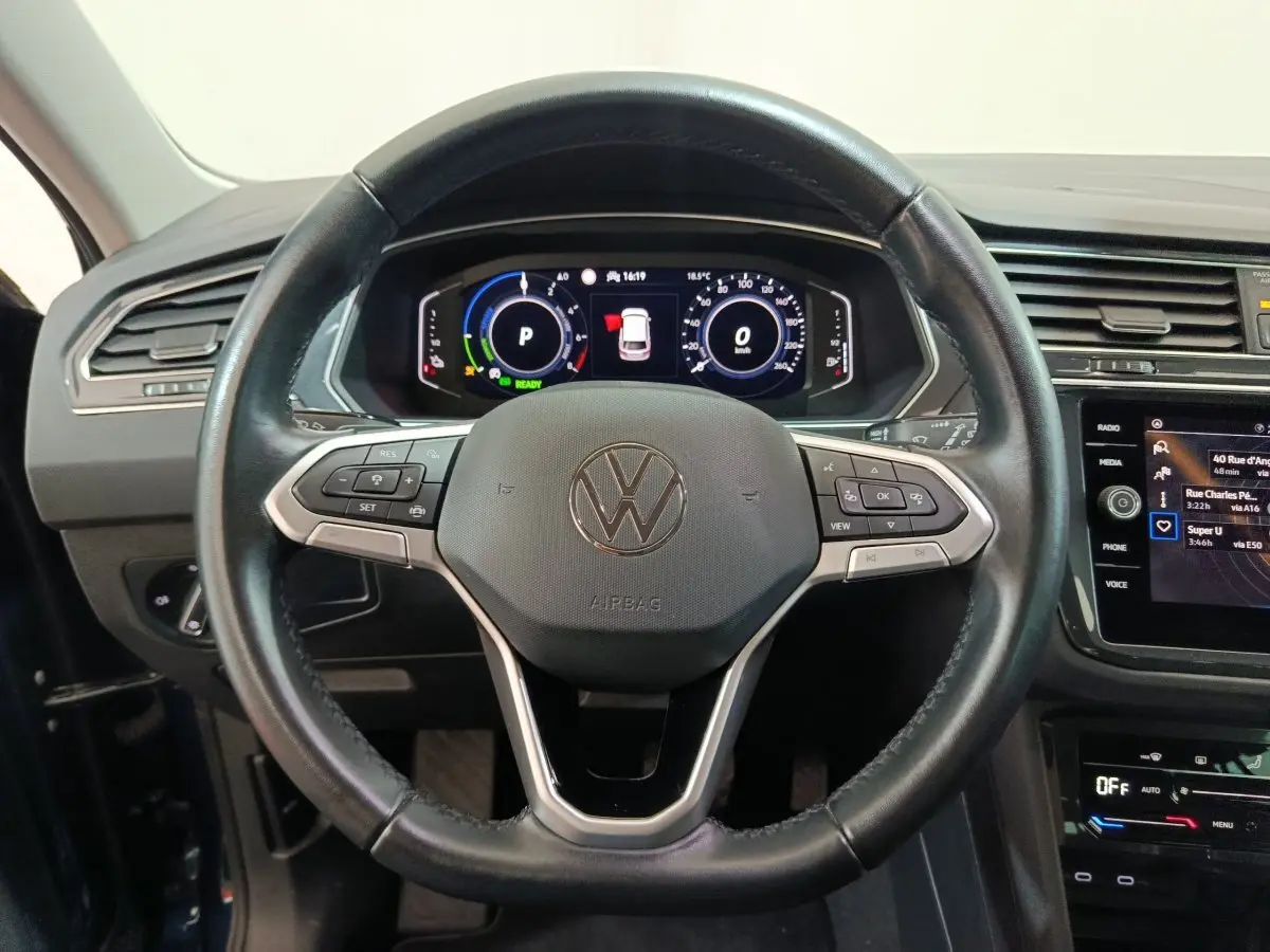 Volant cuir noir et tableau de bord numérique du Volkswagen Tiguan hybride rechargeable 2022 vu de face intérieure.