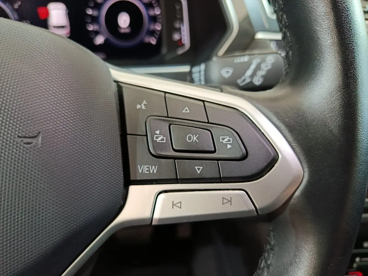 Gros plan sur les commandes multifonctions à droite du volant cuir du Volkswagen Tiguan bleu hybride 2022.