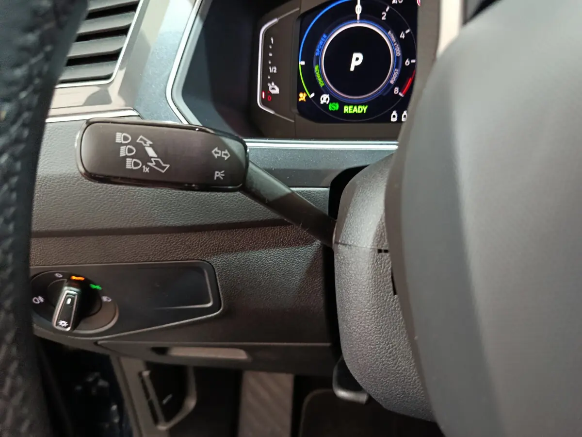 Gros plan sur la manette de clignotant gauche et le tableau de bord numérique du Volkswagen Tiguan bleu hybride rechargeable 2022.