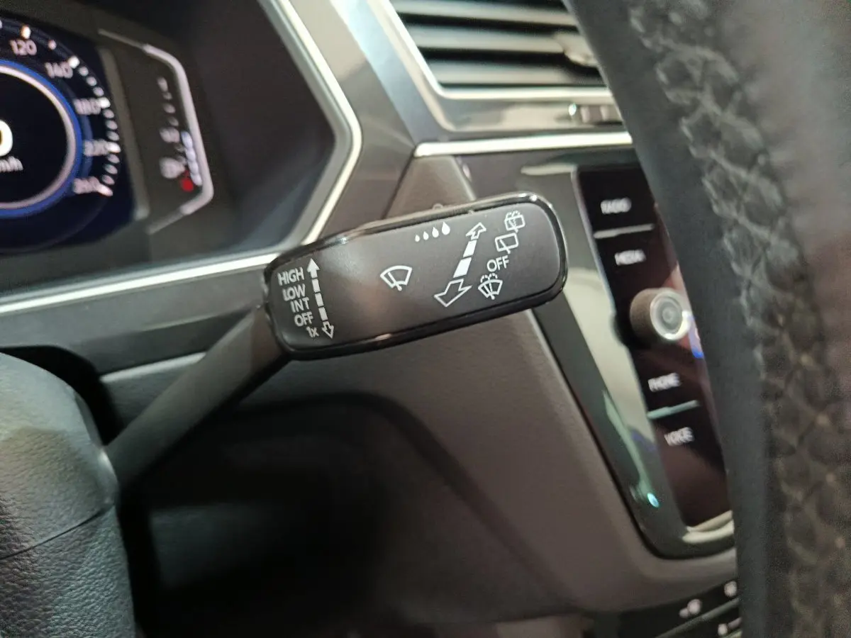 Gros plan sur la commande d'essuie-glace à gauche du volant dans l'habitacle du Volkswagen Tiguan hybride 2022.