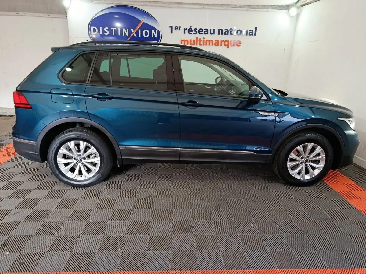 Profil droit d'un Volkswagen Tiguan bleu 2022 hybride rechargeable, avec jantes alliage et badges distinctifs sur ailes.