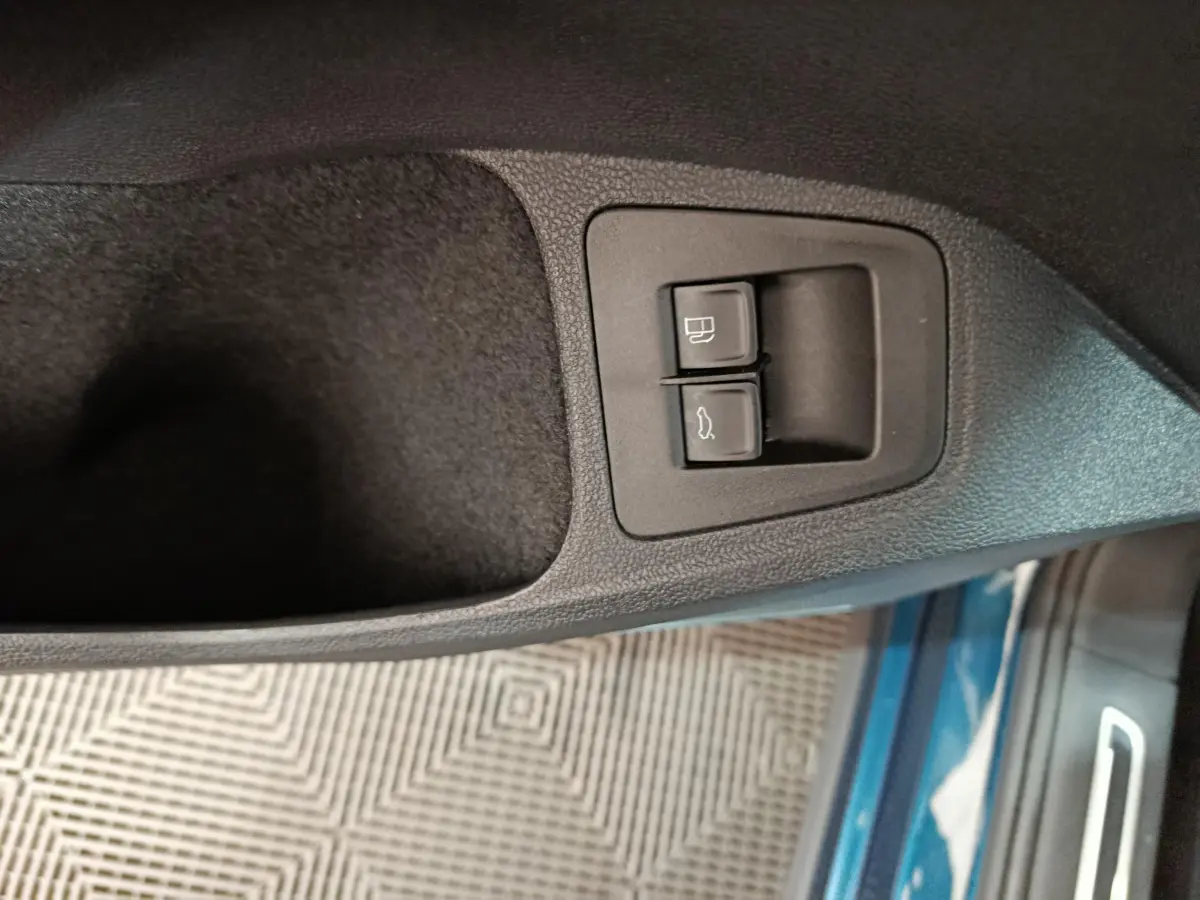 Gros plan sur les boutons d'ouverture du coffre et de la trappe à carburant côté conducteur du Volkswagen Tiguan bleu hybride 2022.