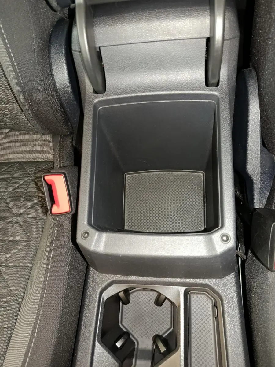 Vue plongeante sur la console centrale noire du Volkswagen Tiguan bleu, avec porte-gobelets et rangement vide.