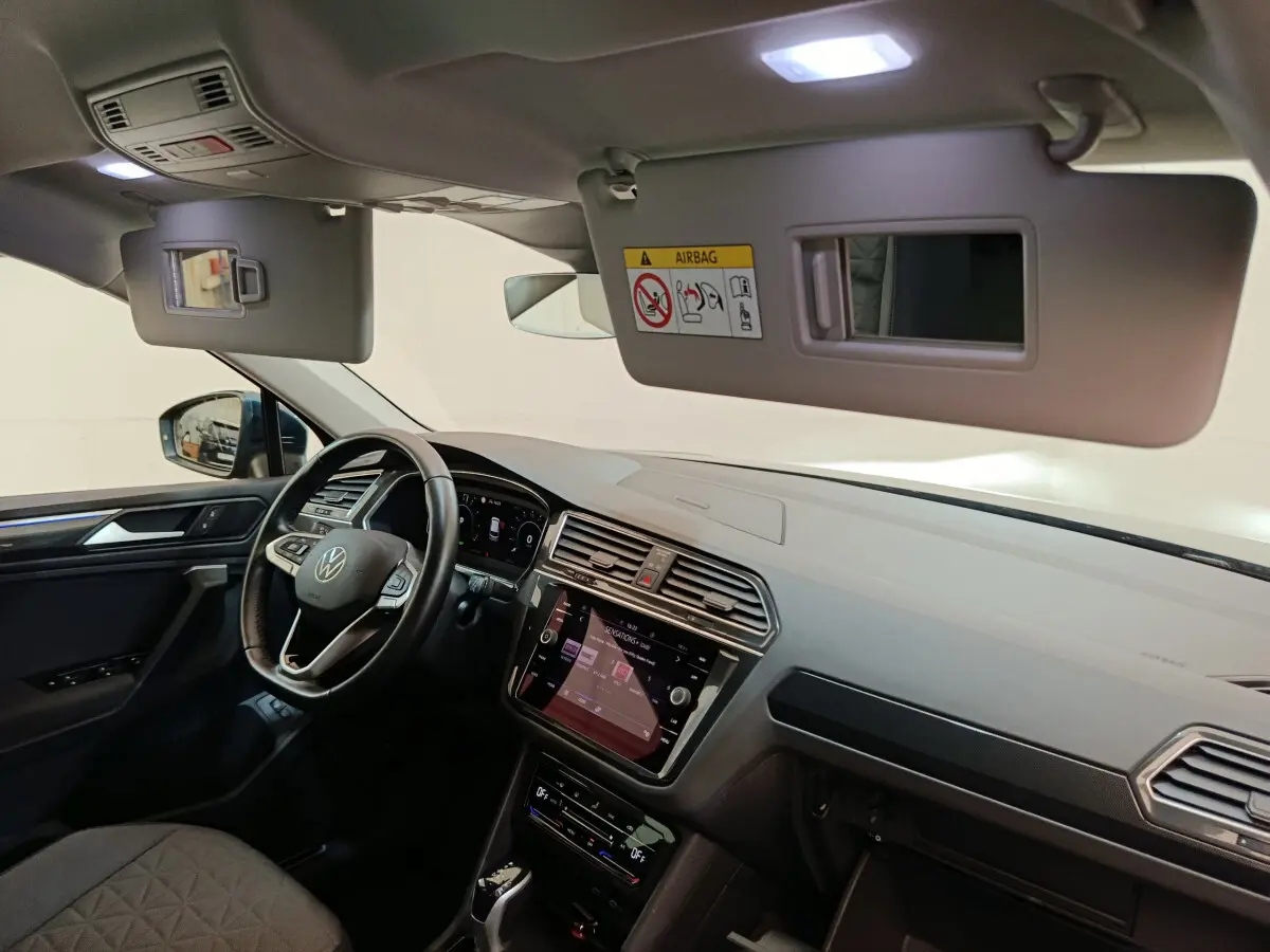 Vue intérieure côté conducteur du tableau de bord et volant cuir du Volkswagen Tiguan bleu 2022 hybride rechargeable.