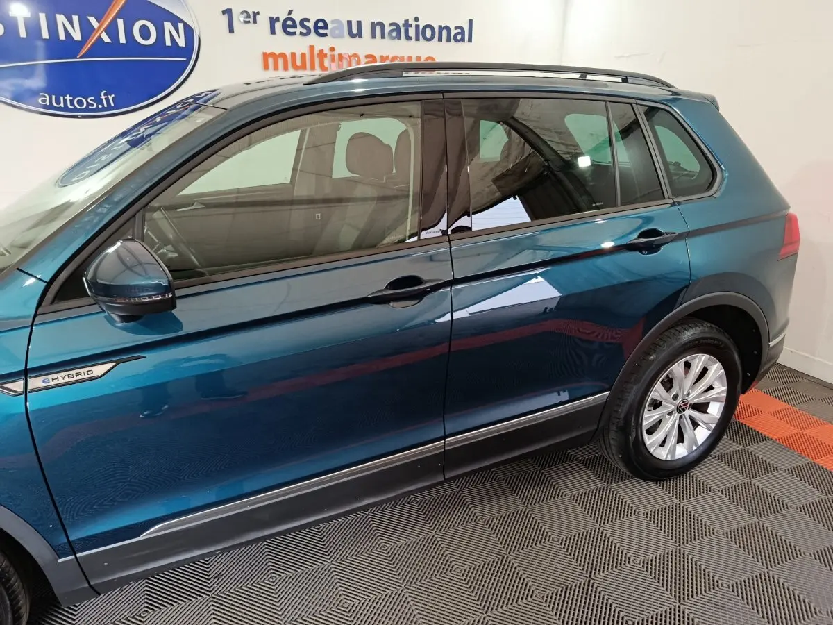 Vue latérale côté gauche d'un Volkswagen Tiguan bleu hybride rechargeable avec badge eHybrid et jantes argentées.
