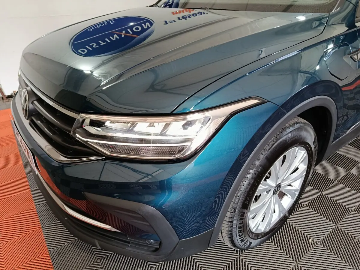 Vue 3/4 avant droit du Volkswagen Tiguan bleu 2022 avec phares LED et jante alliage visible.