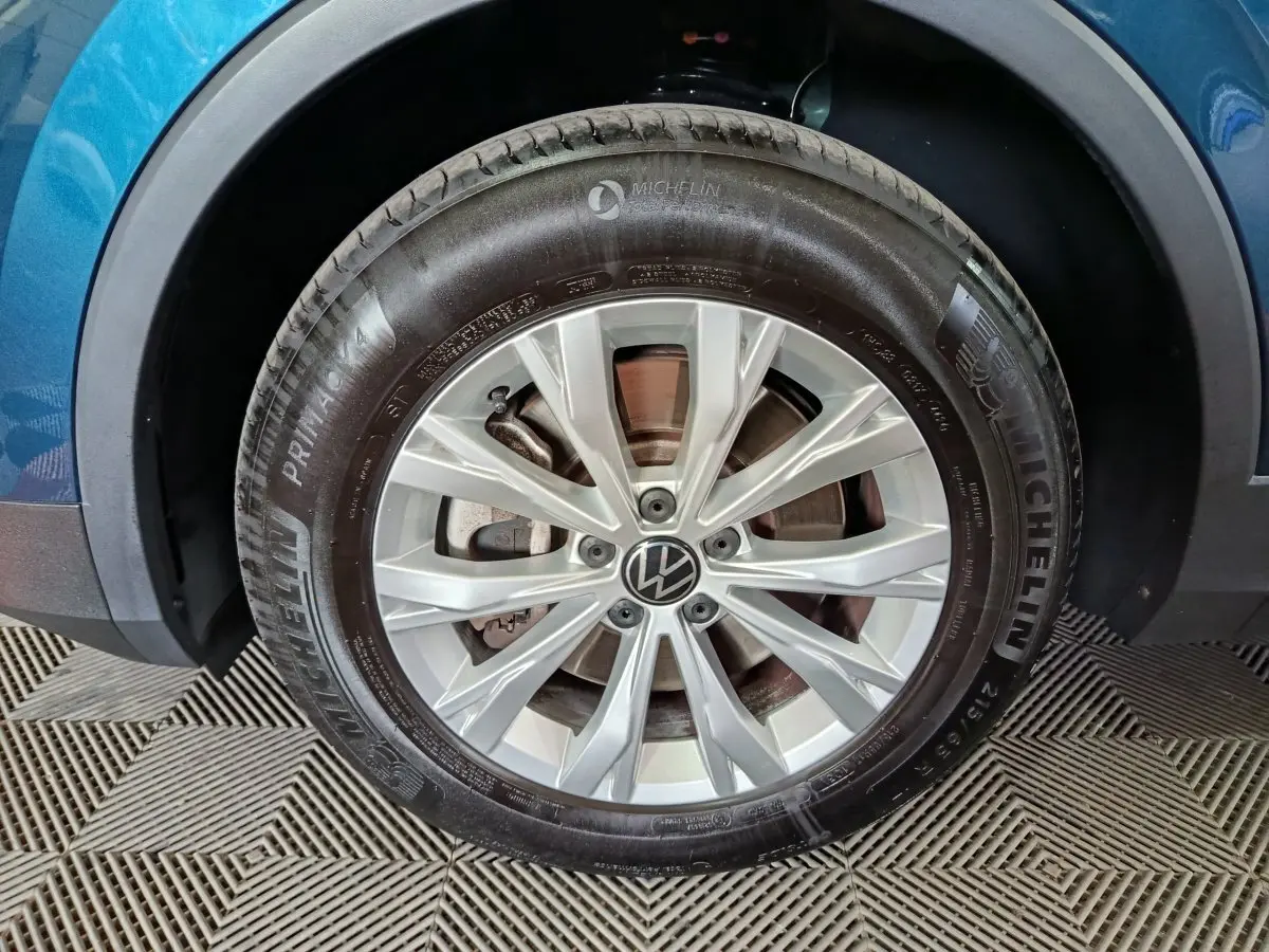 Gros plan sur la roue avant gauche d'un Volkswagen Tiguan bleu 2022 avec jante alliage et pneu Michelin
