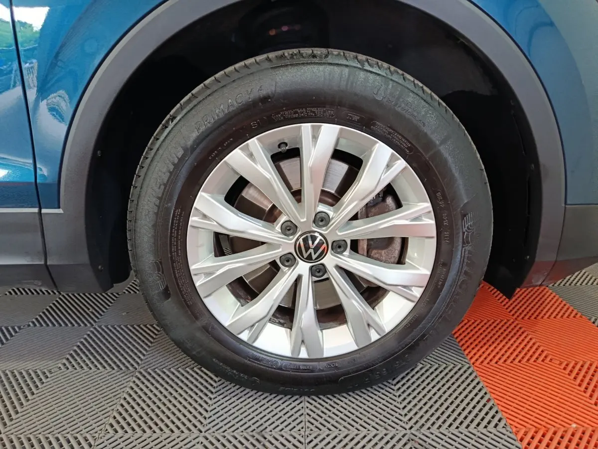 Gros plan sur la roue avant droite du Volkswagen Tiguan bleu 1.4 EHYBRID avec jante alliage à rayons fins.