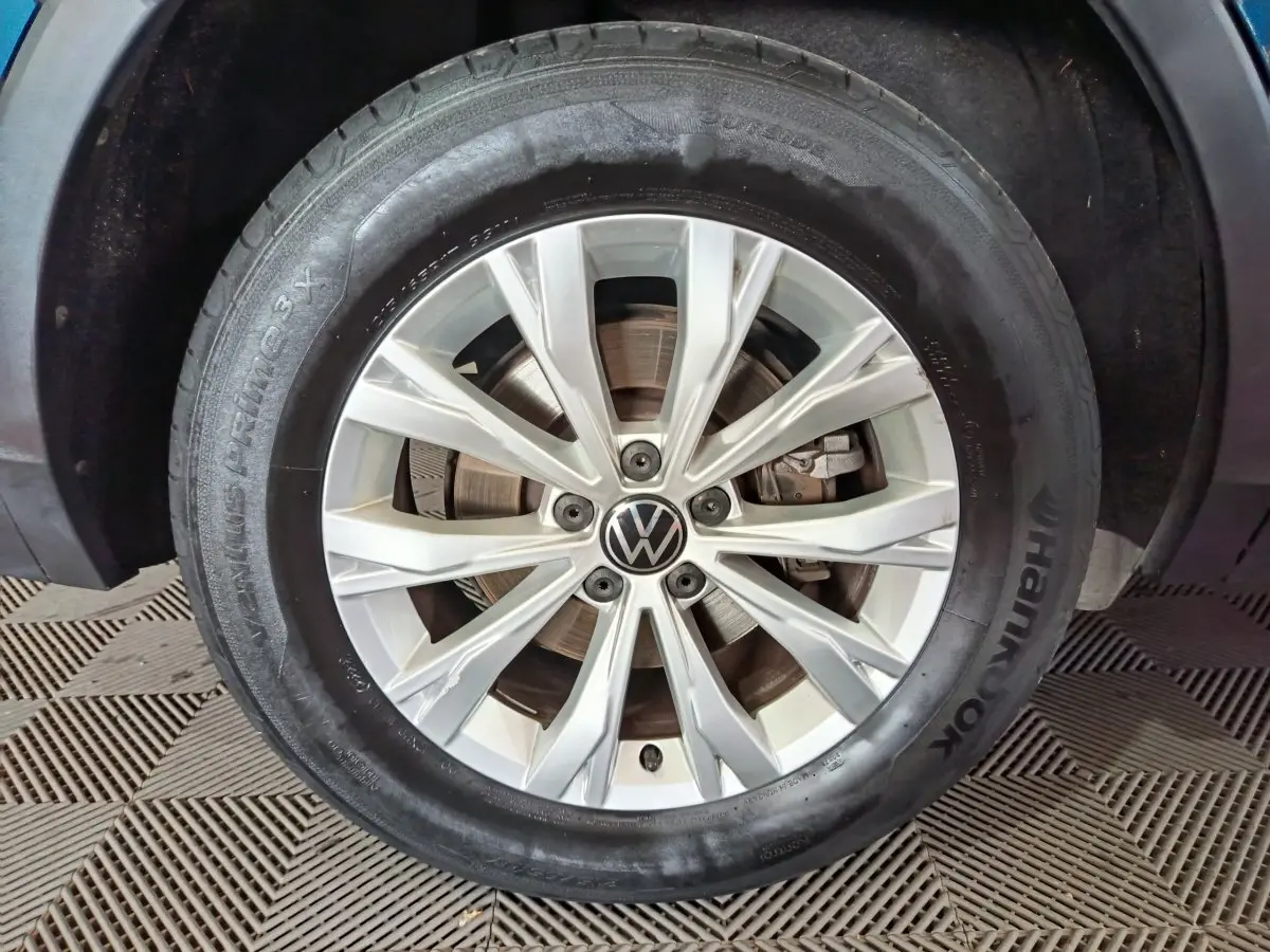 Gros plan sur la jante alliage argentée et pneu Hankook d'un Volkswagen Tiguan bleu hybride rechargeable 2022.