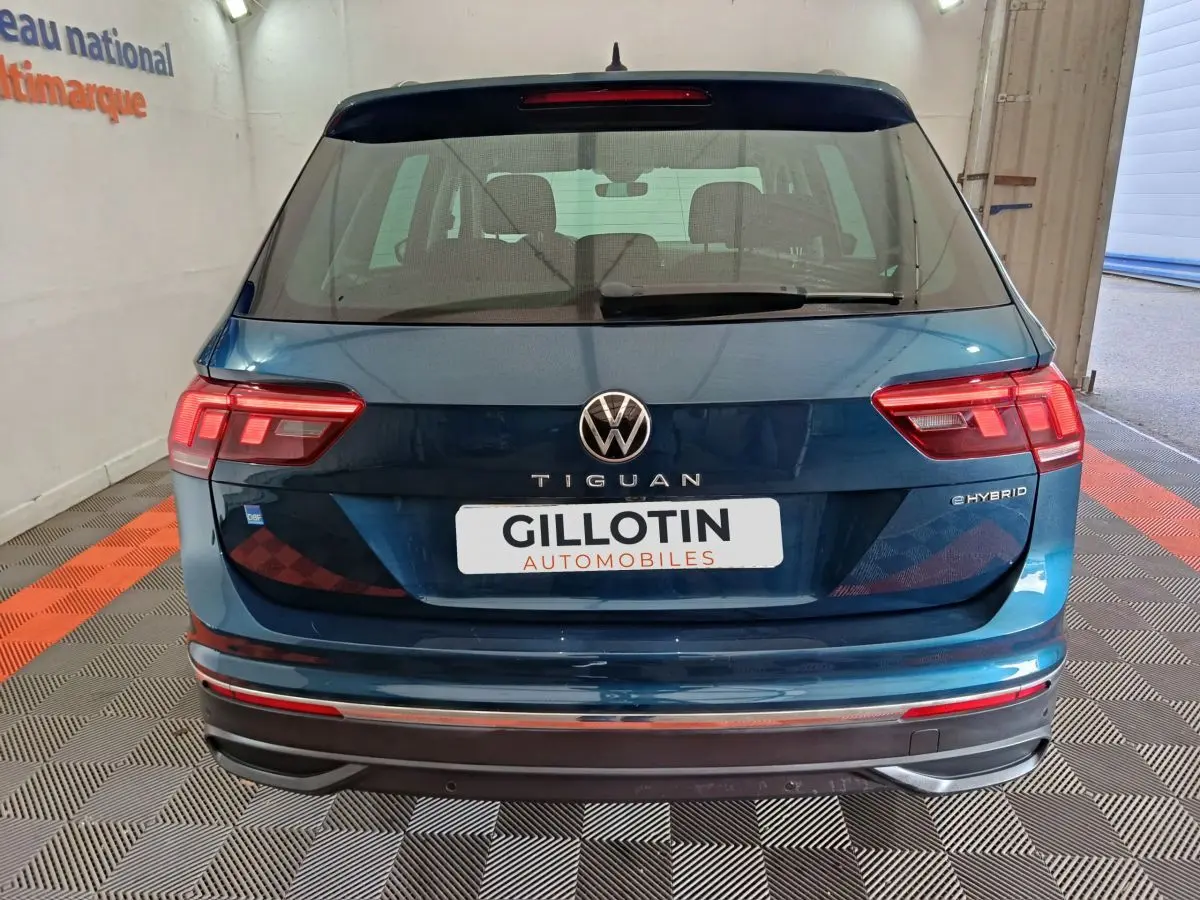 Vue arrière d'un Volkswagen Tiguan bleu hybride rechargeable 2022 avec feux LED et logo eHYBRID visible.