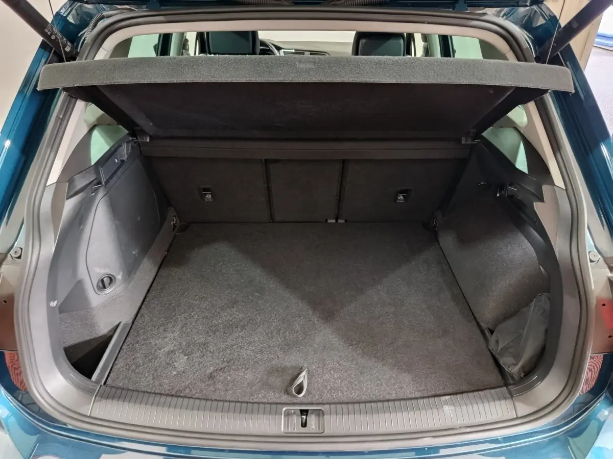 Coffre ouvert vu de l'arrière d'un Volkswagen Tiguan bleu, montrant un espace de chargement propre et spacieux.