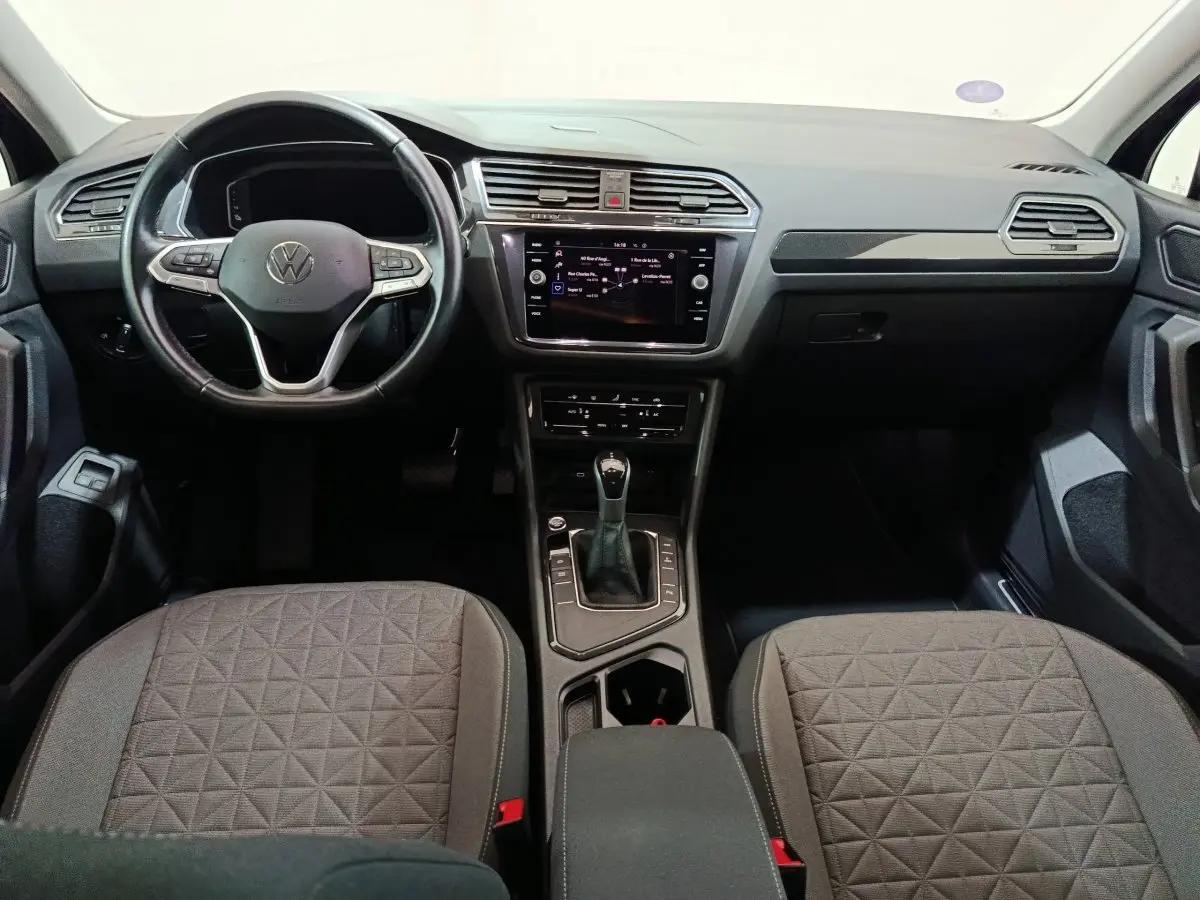 Intérieur du Volkswagen Tiguan 1.4 eHybrid 2022, vue frontale du tableau de bord et sièges gris à motifs géométriques.