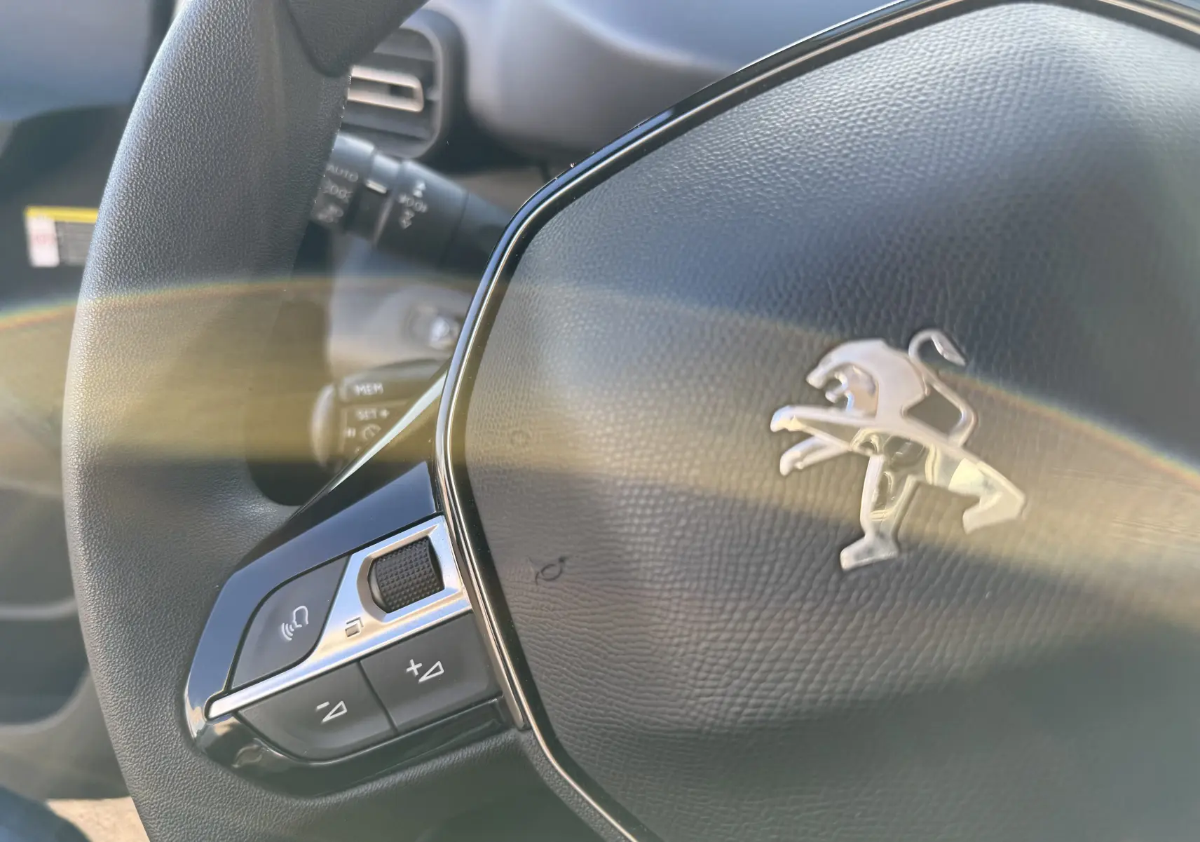 Gros plan sur le volant noir du Peugeot Rifter gris platinium 2020, avec commandes intégrées côté gauche.