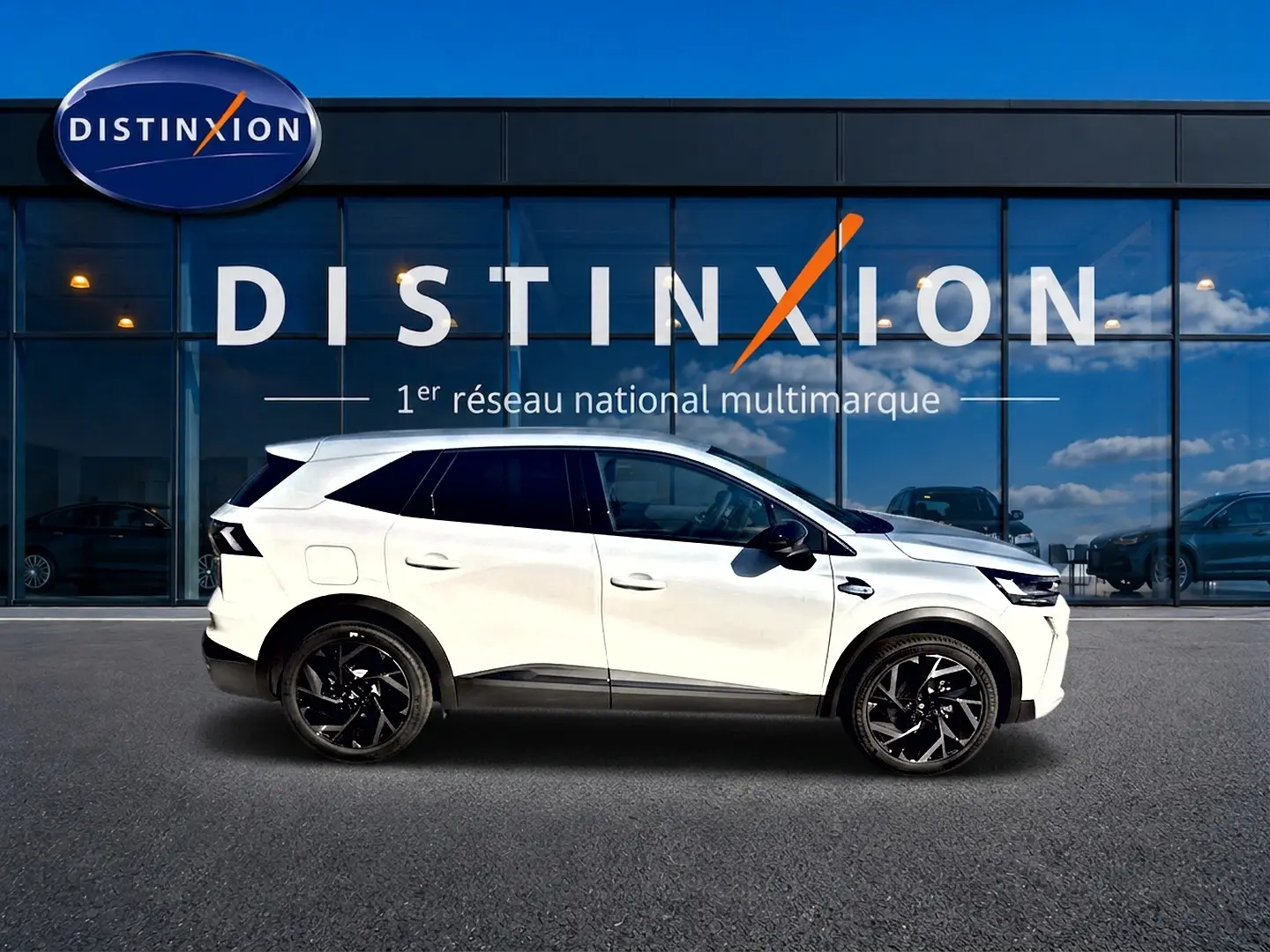 Vue latérale gauche d'un Renault Symbioz blanc nacré avec jantes noires, devant une vitrine Distinxion.