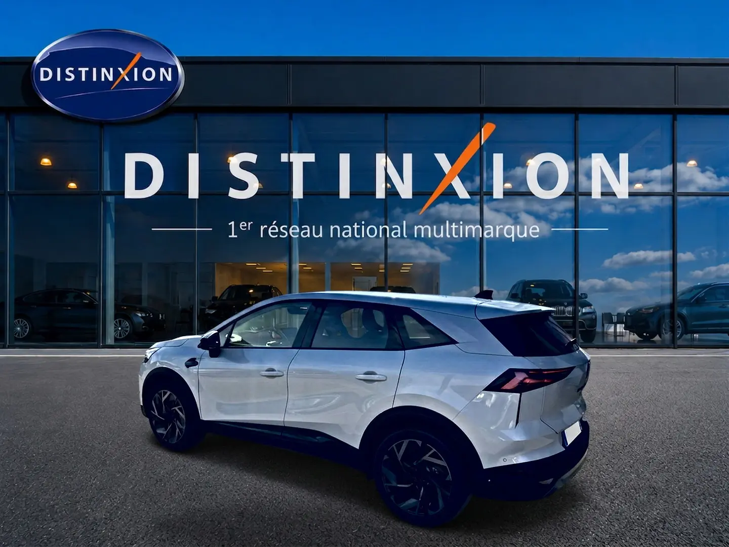 Vue latérale gauche d'un Renault Symbioz blanc nacré avec jantes noires, devant une vitrine Distinxion.