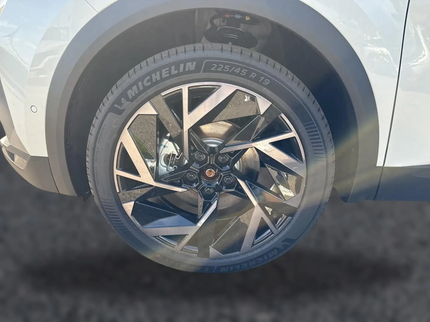 Gros plan sur la roue avant droite du Renault Symbioz blanc nacré avec jante alu noire et argentée au design géométrique.