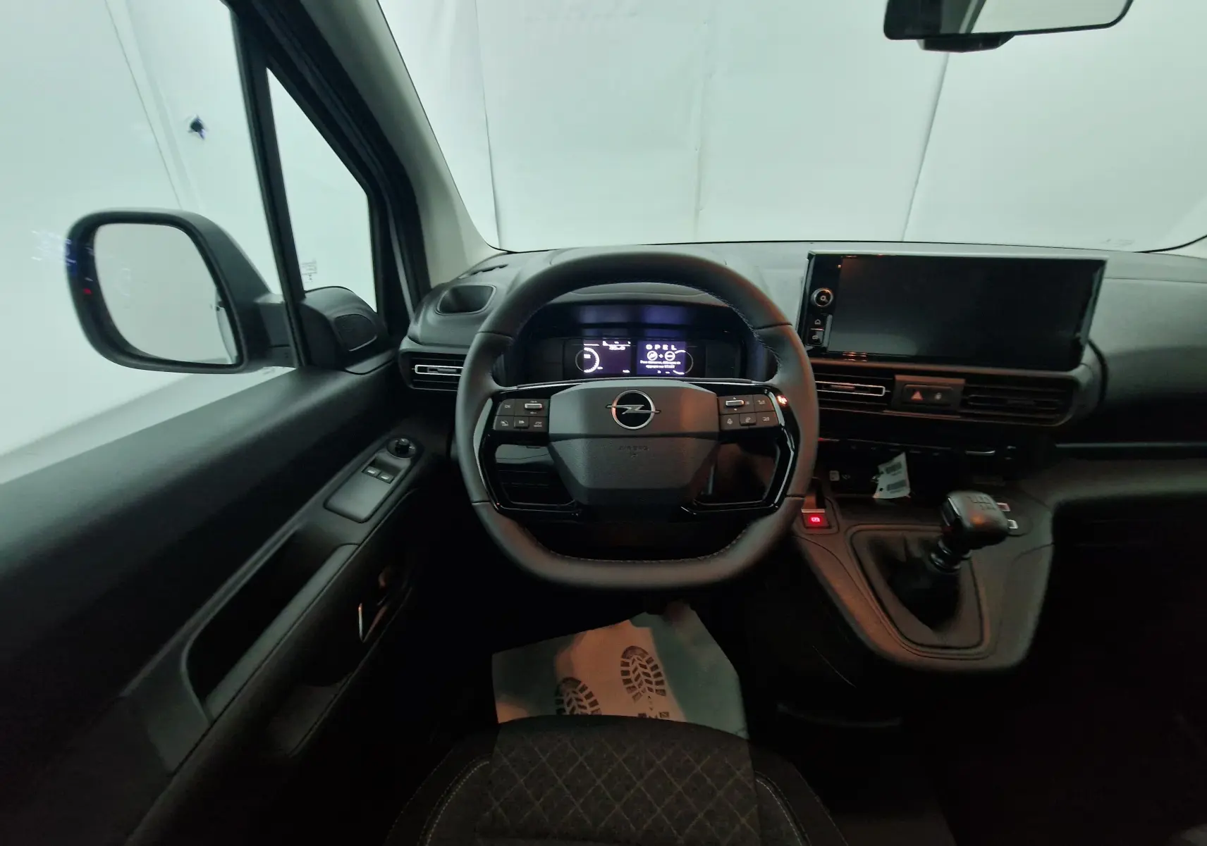 Vue intérieure côté conducteur de l'Opel Combo Life blanc, avec volant multifonction et boîte manuelle visible.