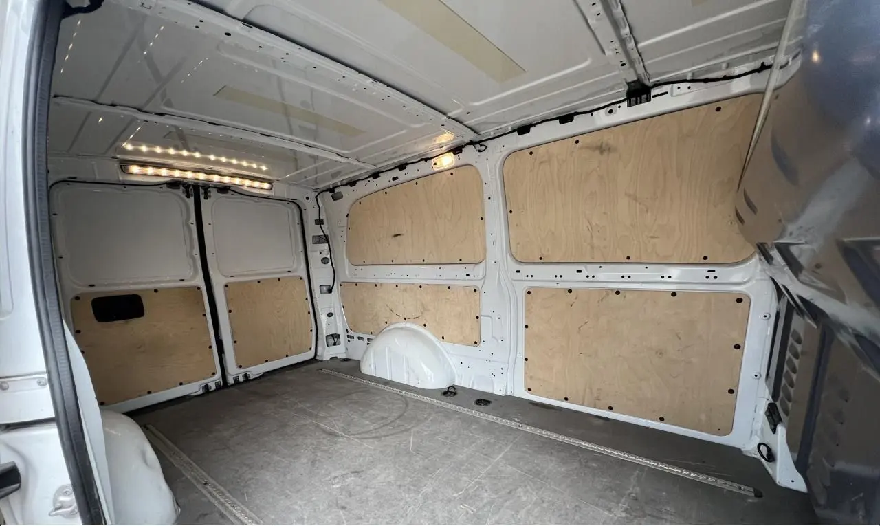 Vue intérieure arrière du fourgon blanc Mercedes Vito Extra Long 2021, avec habillage bois et plancher gris.