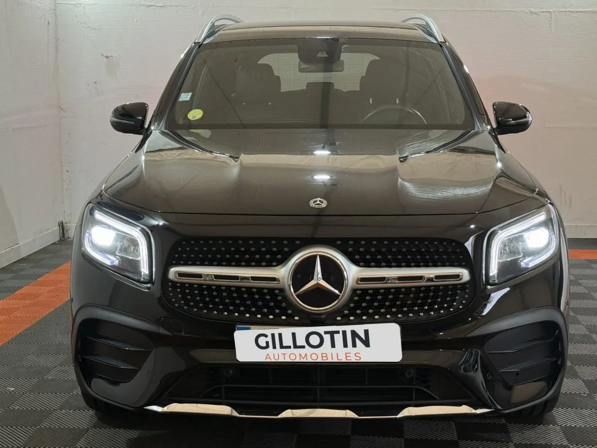 Vue frontale d'un Mercedes GLB 200 d AMG Line noir avec phares LED allumés et calandre distinctive AMG.