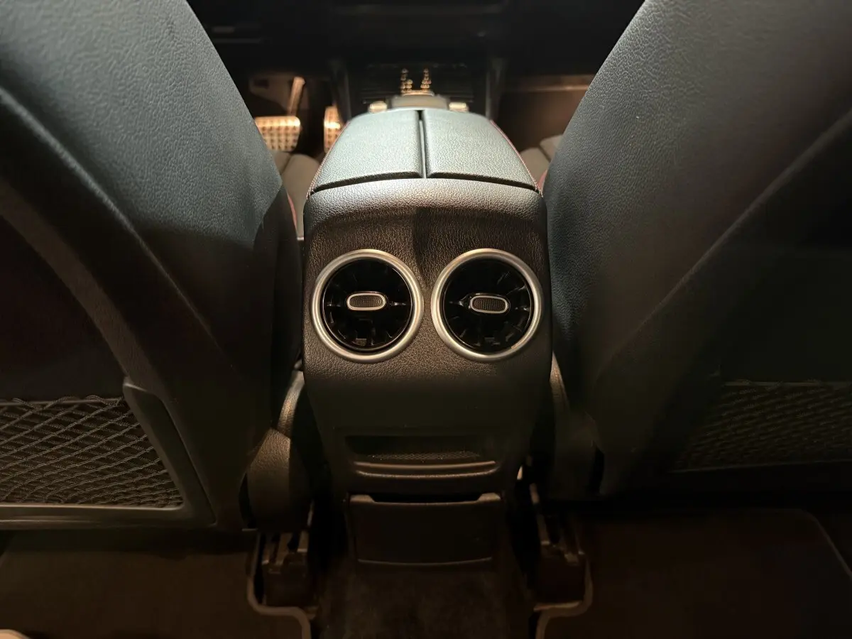 Vue rapprochée de l'espace entre les sièges avant noirs du Mercedes GLB 200 d AMG Line, intérieur sombre.